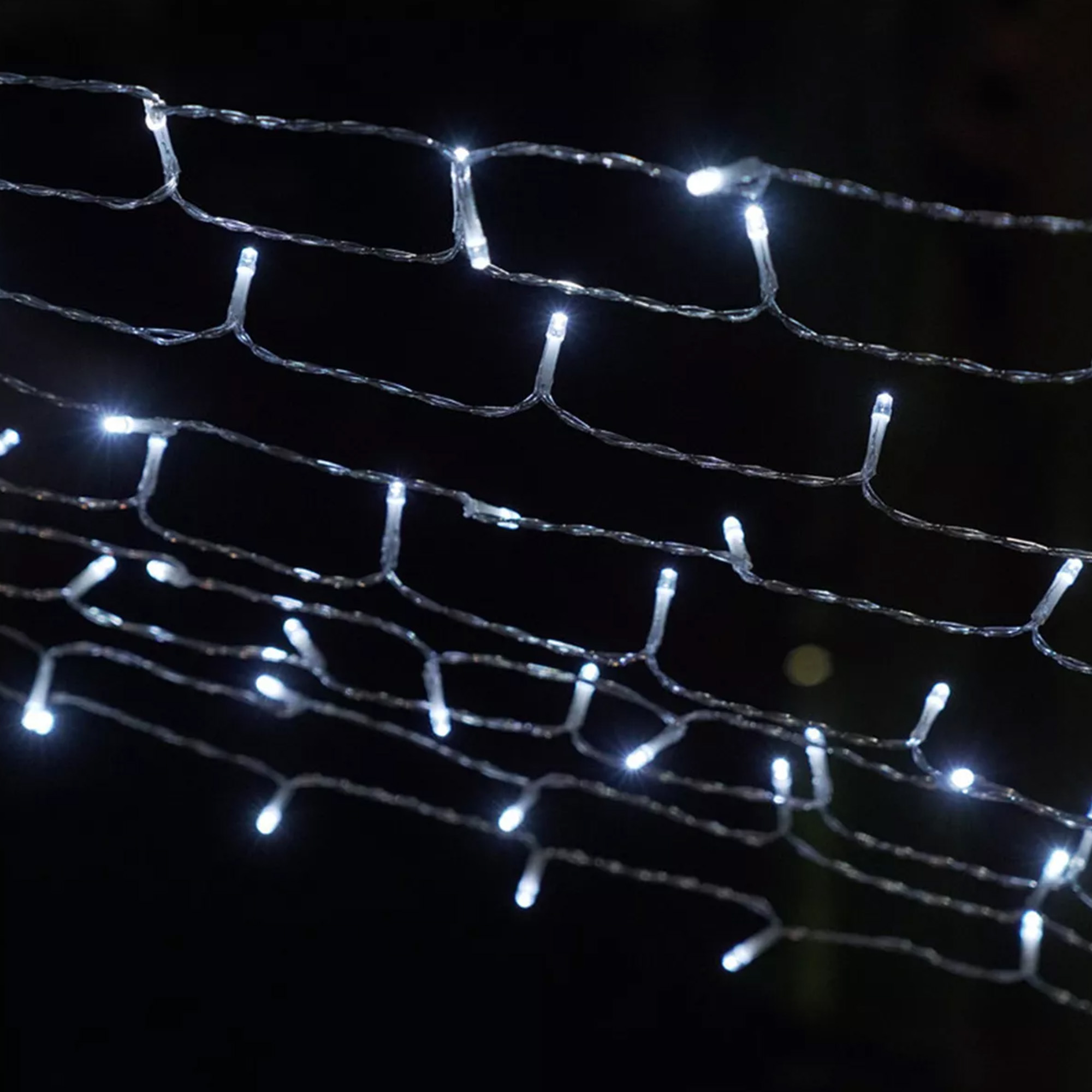 Primer plano de luces navideñas blancas sobre un fondo oscuro. Las luces están dispuestas en filas.