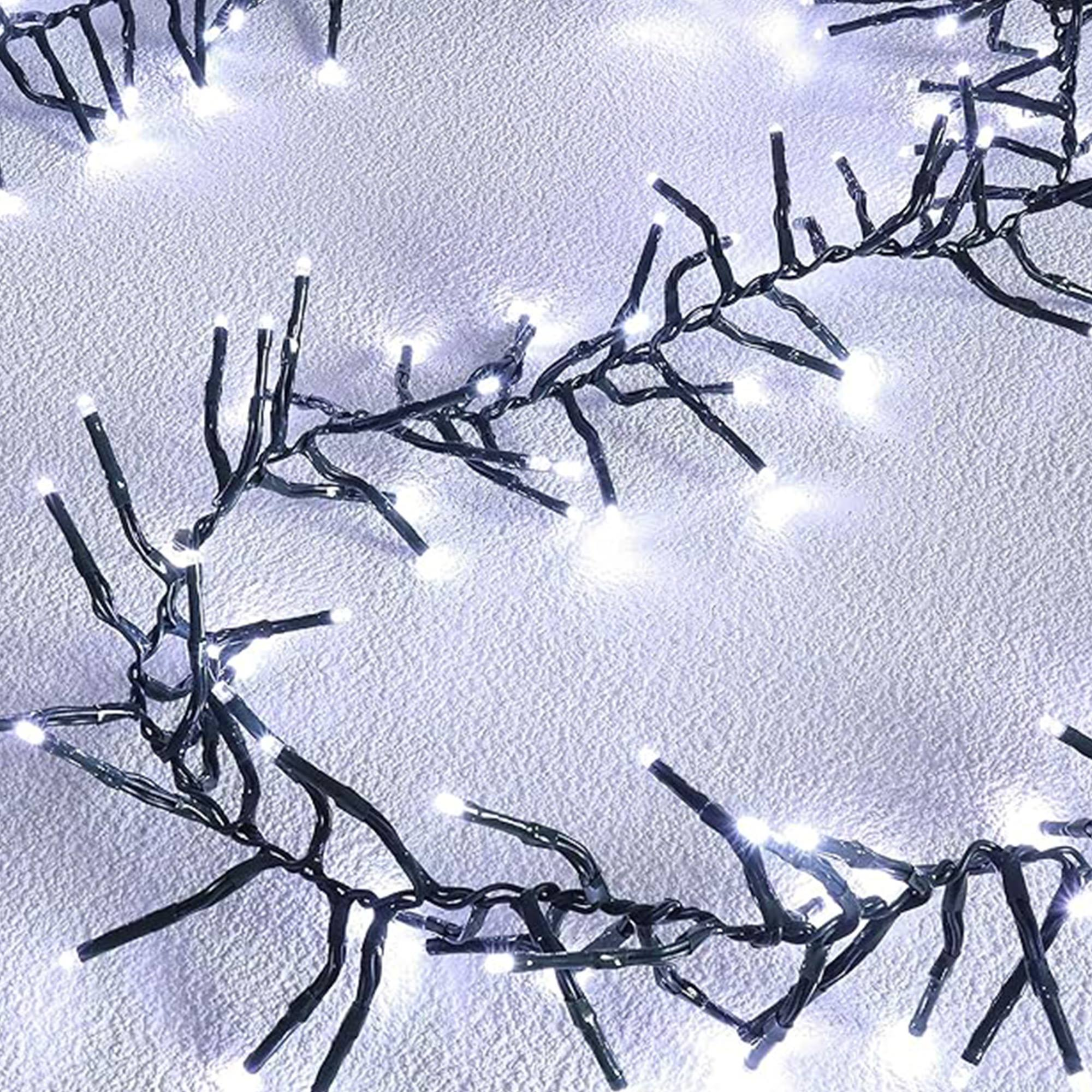 Cadena de luces LED blancas sobre una superficie blanca y texturizada. Cables verde oscuro forman las ramas que sostienen las luces.