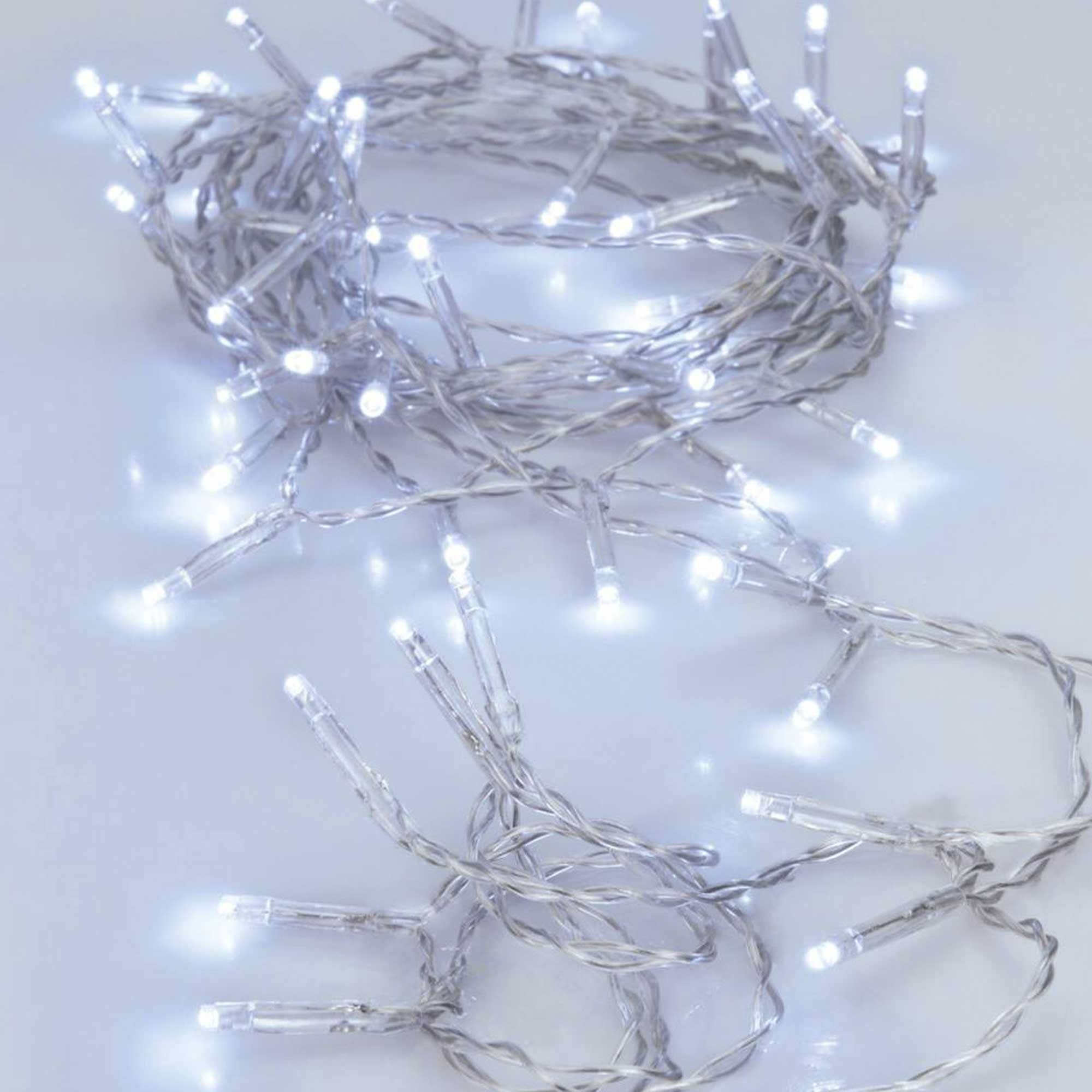 Cadena de luces LED blancas sobre un cable gris, dispersas sobre una superficie blanca. Las luces están encendidas y brillando.