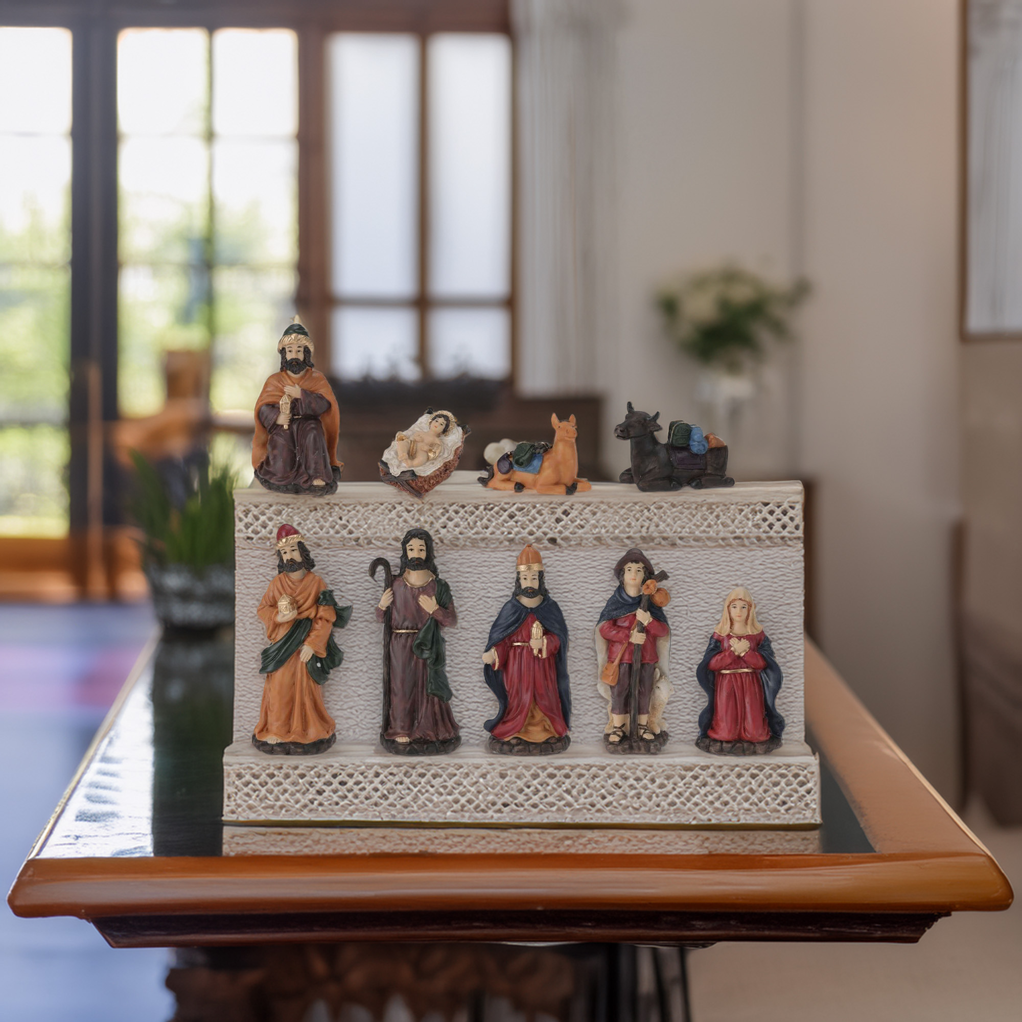 Un belén con figuras sobre una mesa. Las figuras incluyen a María, José, el niño Jesús y animales.