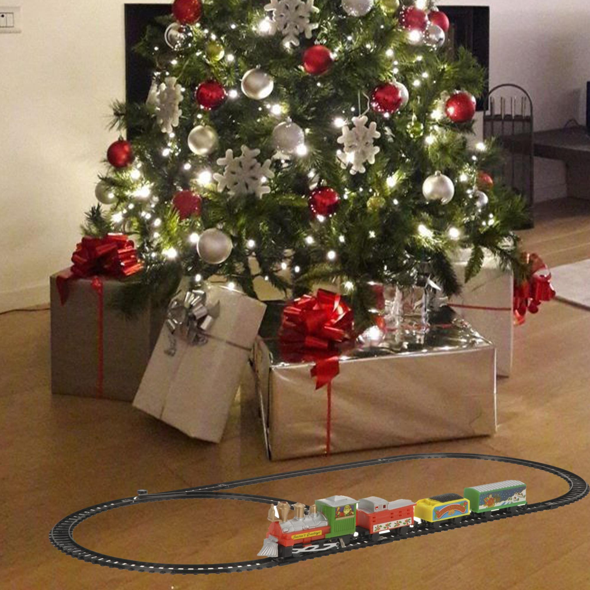 Un árbol de Navidad decorado con regalos debajo. Un tren de juguete circula sobre raíles en primer plano.
