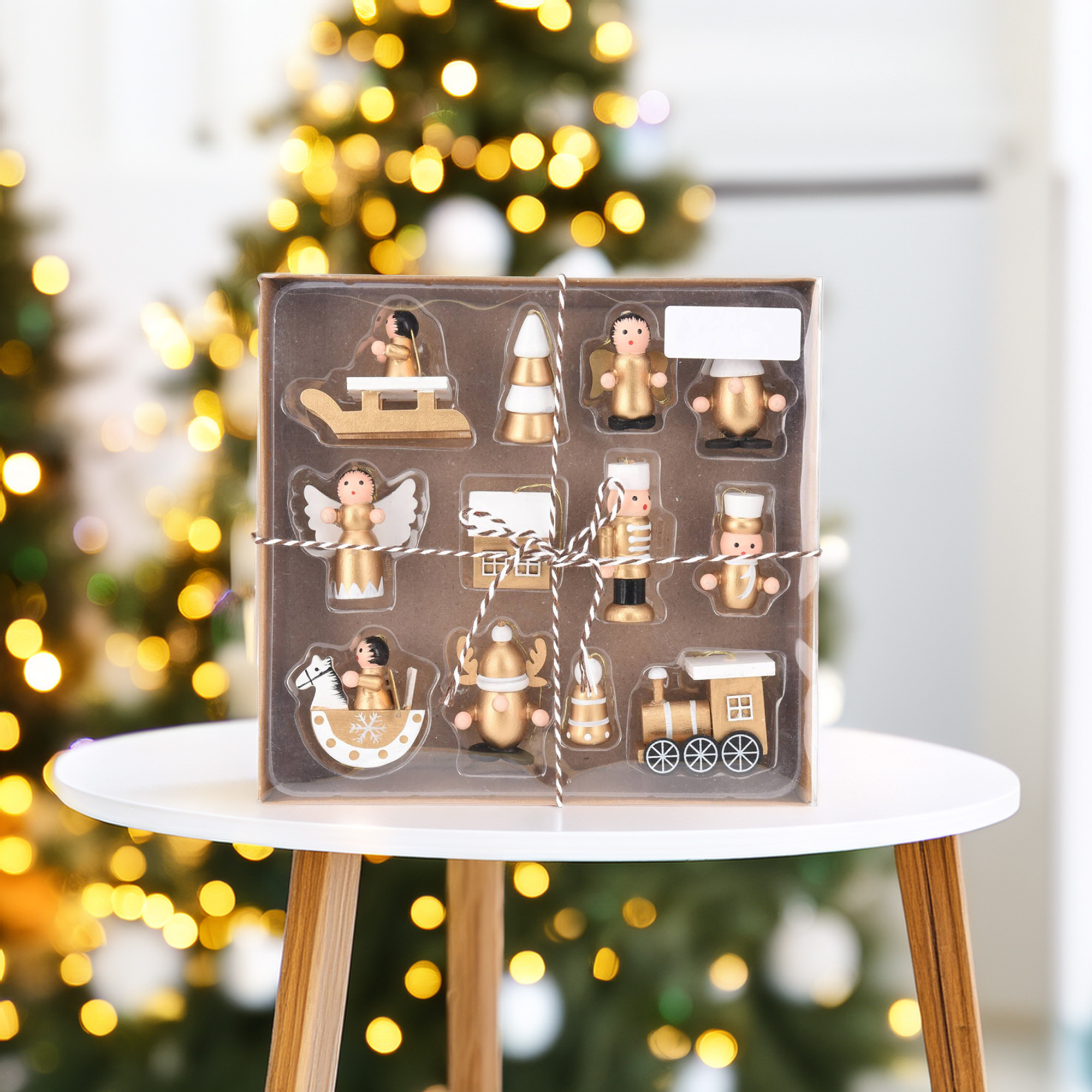Caja de adornos navideños en una mesa blanca. Incluye ángeles, tren, cascanueces, árbol, reno y caballito balancín.