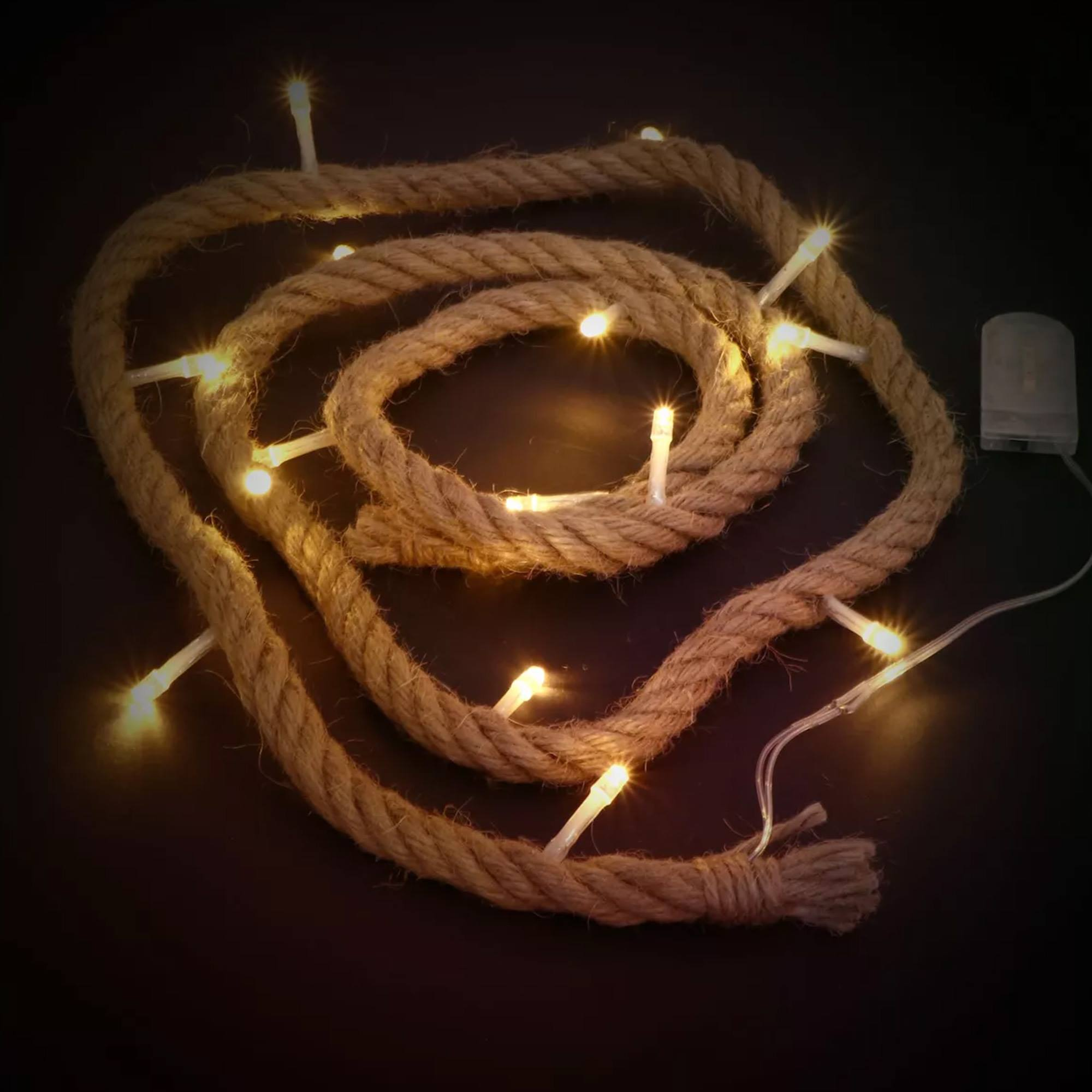 Una cuerda enrollada con luces de hadas incrustadas. Las luces son blanco cálido sobre un fondo oscuro, con una batería.