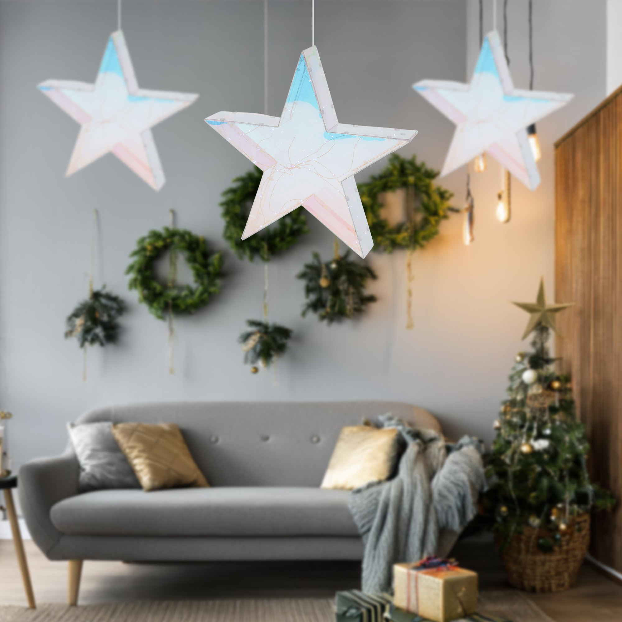 Un salón decorado para Navidad. Tres adornos en forma de estrella cuelgan del techo. Se ven un sofá y un árbol de Navidad.