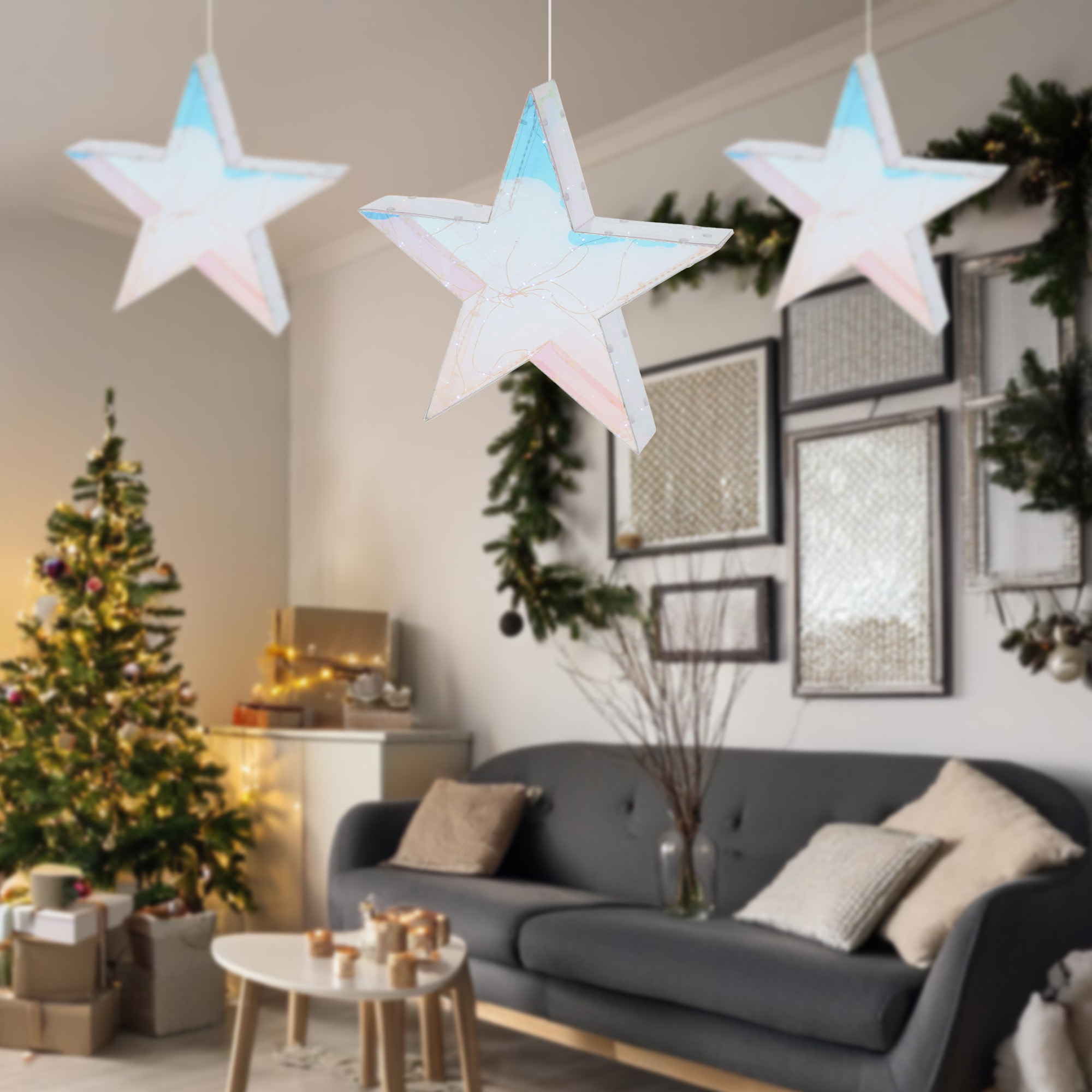 Una sala decorada con un árbol de Navidad, adornos de estrellas, un sofá gris y cuadros en la pared.