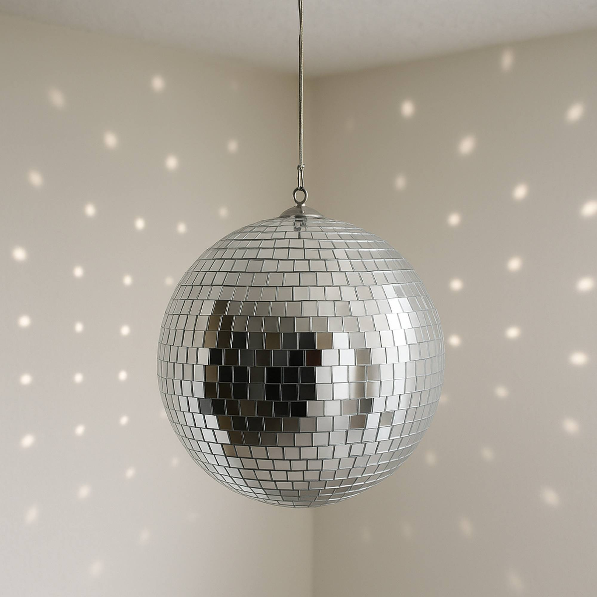 Una bola de discoteca cuelga del techo. Está cubierta de pequeños espejos. La luz se refleja en las paredes, creando puntos.