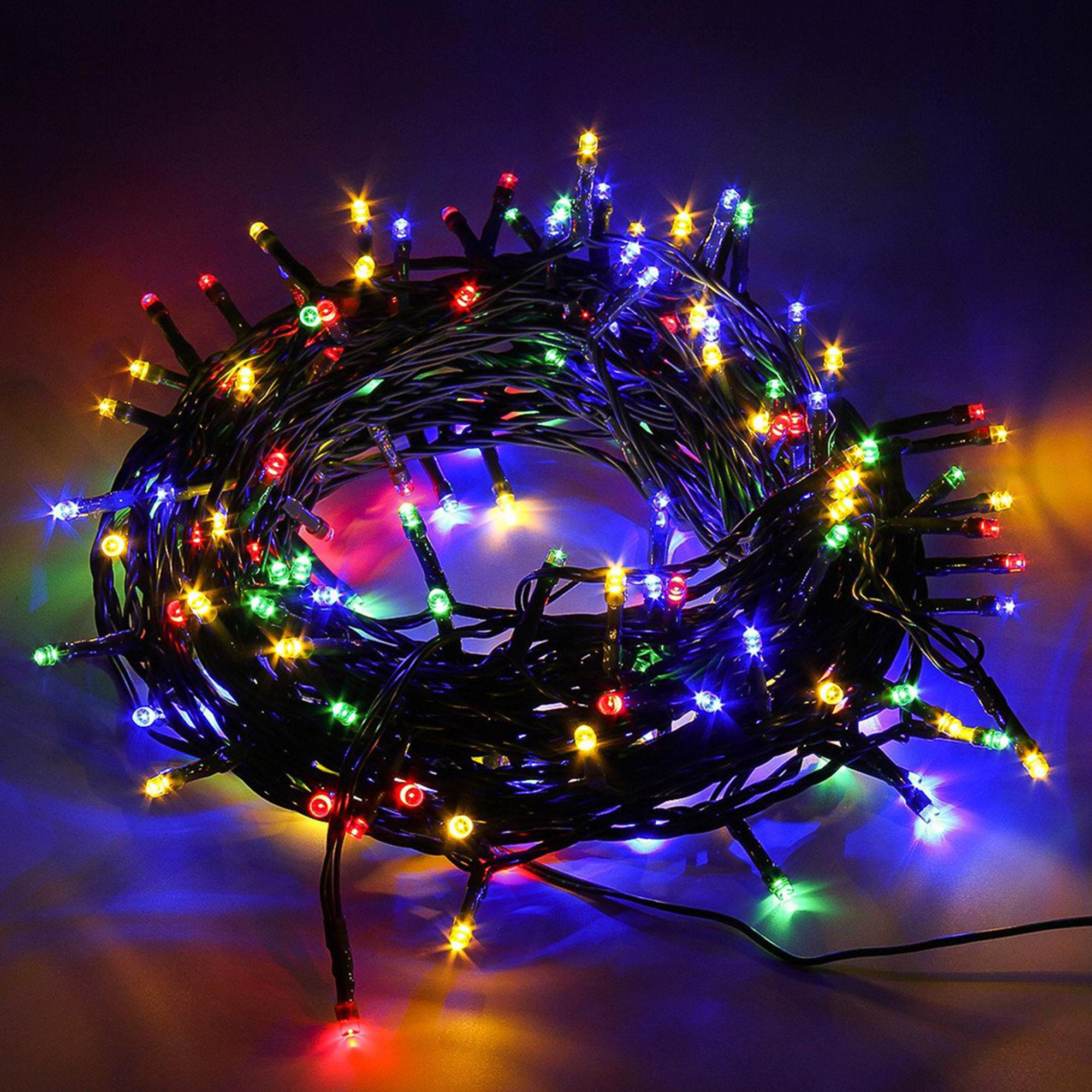 Un montón de luces navideñas de colores. Varios colores iluminan sobre un fondo oscuro. Las luces están en un cable negro.