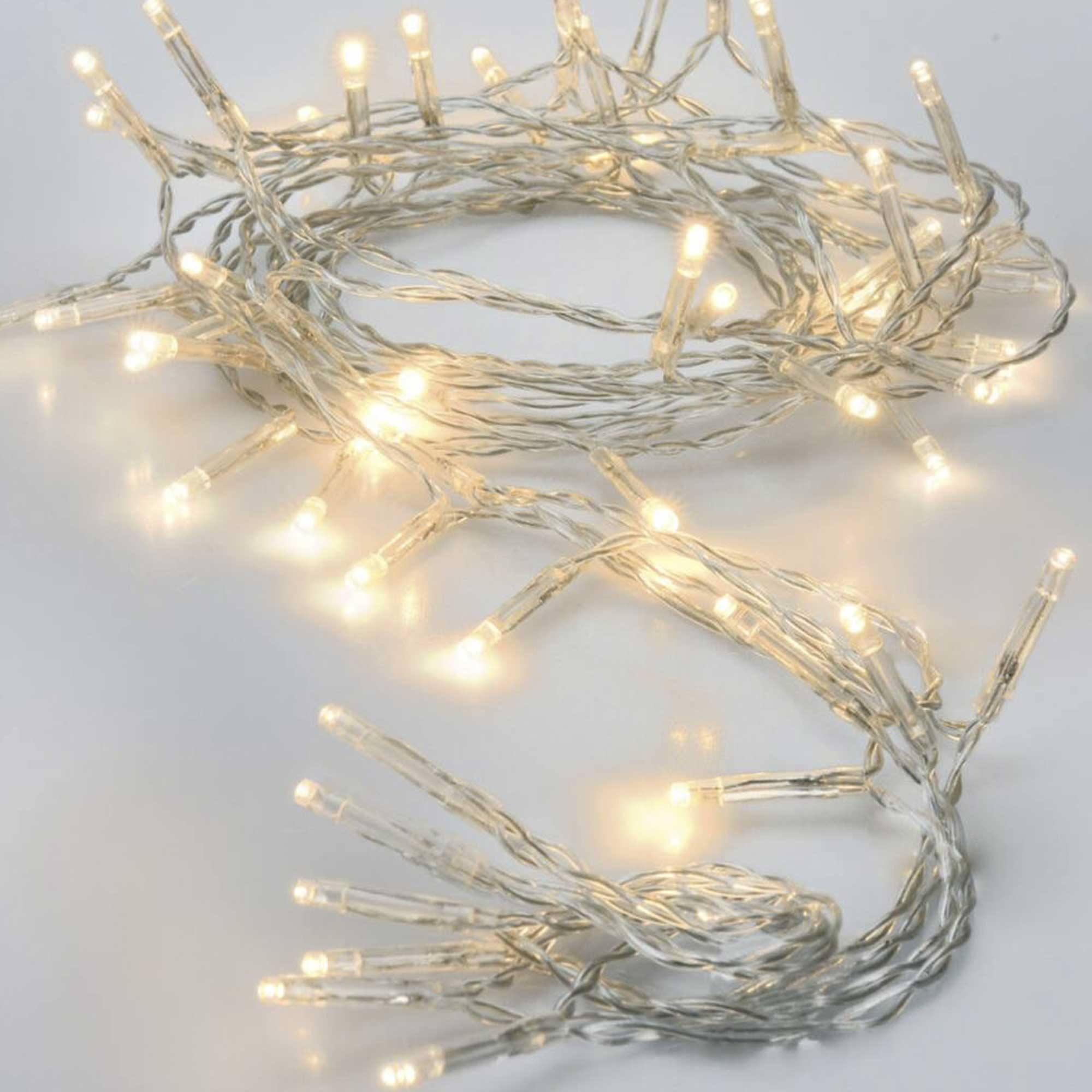 Una cadena de luces LED blanco cálido. Las luces están encendidas y los cables son plateados. El fondo es blanco.
