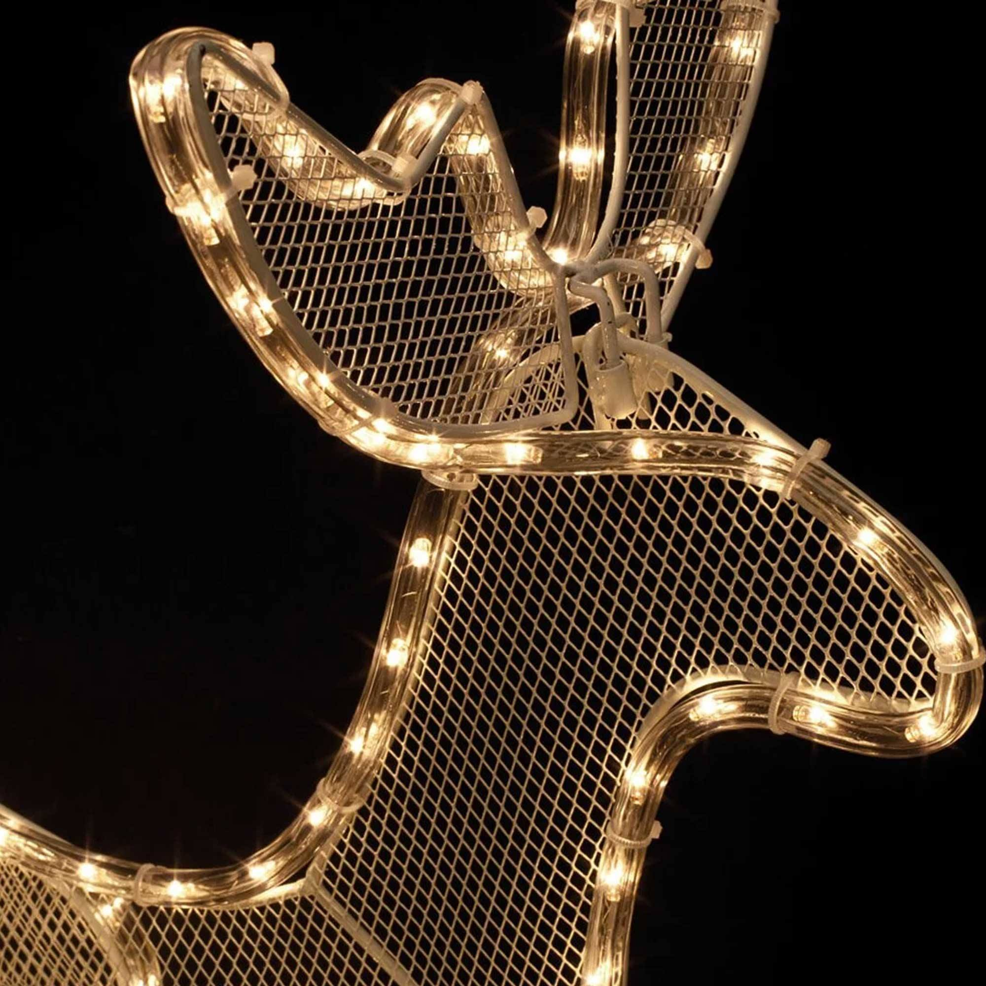 Una decoración de reno de metal blanco con luces blanco cálido sobre fondo negro. Las astas están iluminadas.
