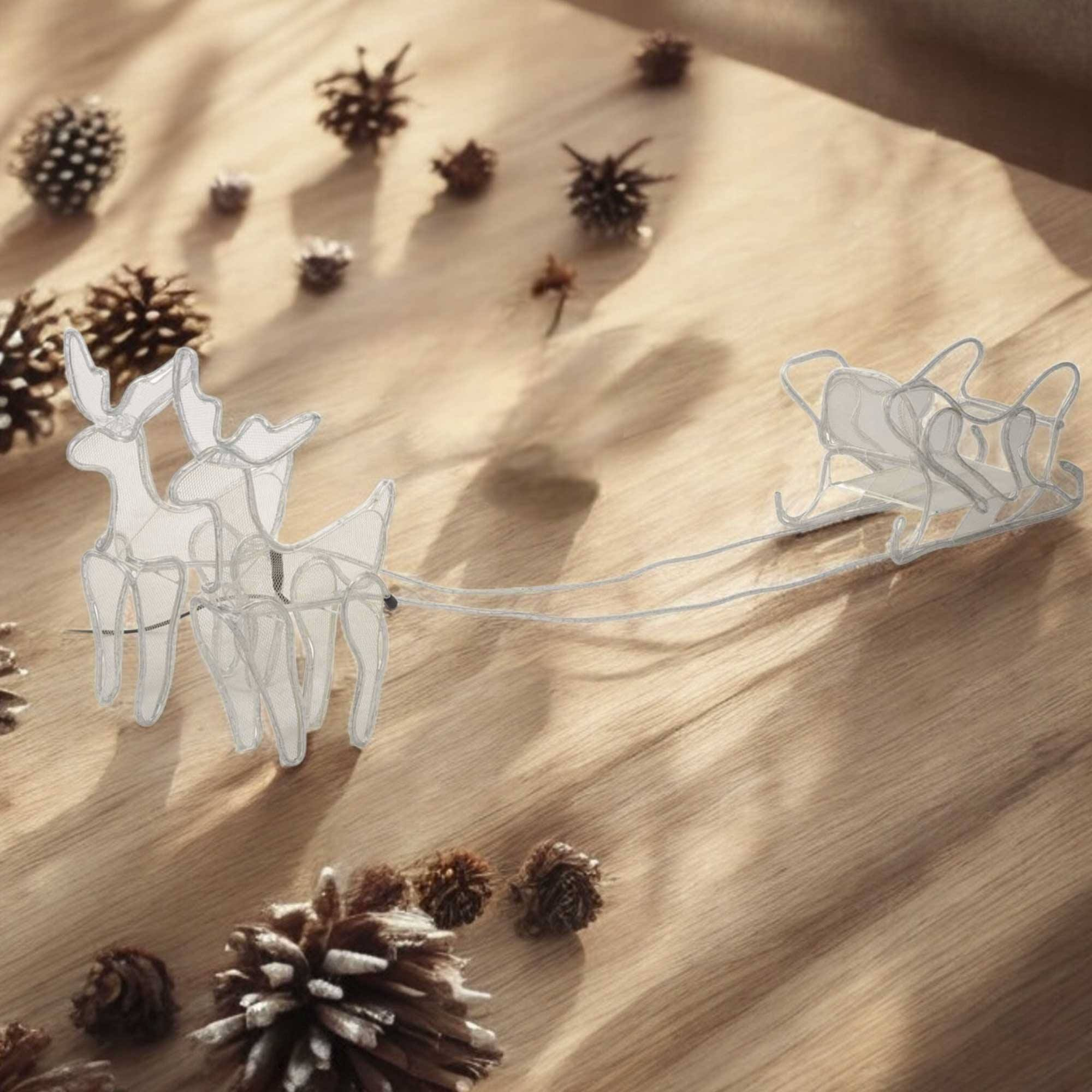 Renos y trineo blancos sobre una superficie de madera con piñas. Escena navideña decorativa. Hay sombras.