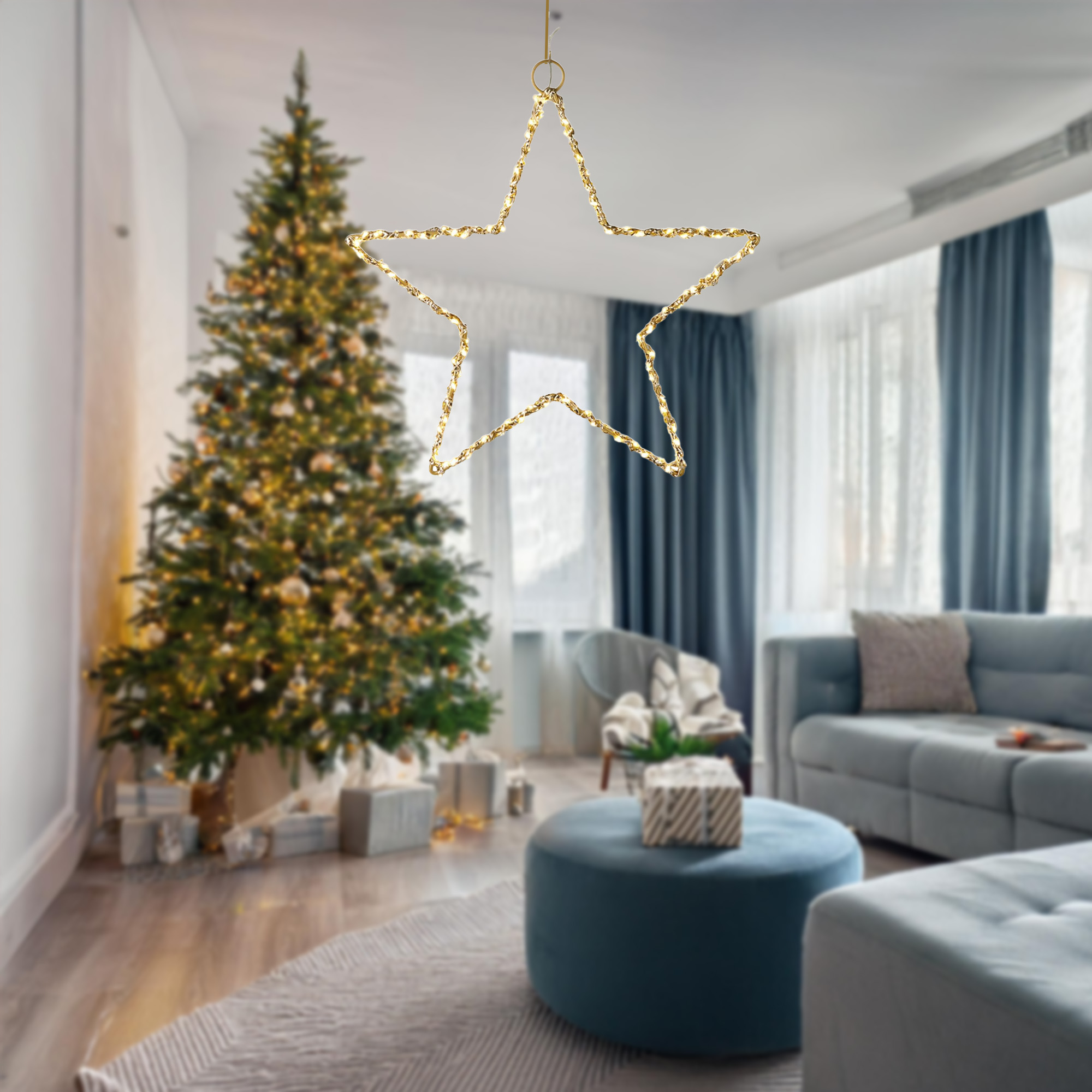Una estrella decorativa iluminada cuelga en una sala de estar con un árbol de Navidad, regalos, sofá y cortinas azules.