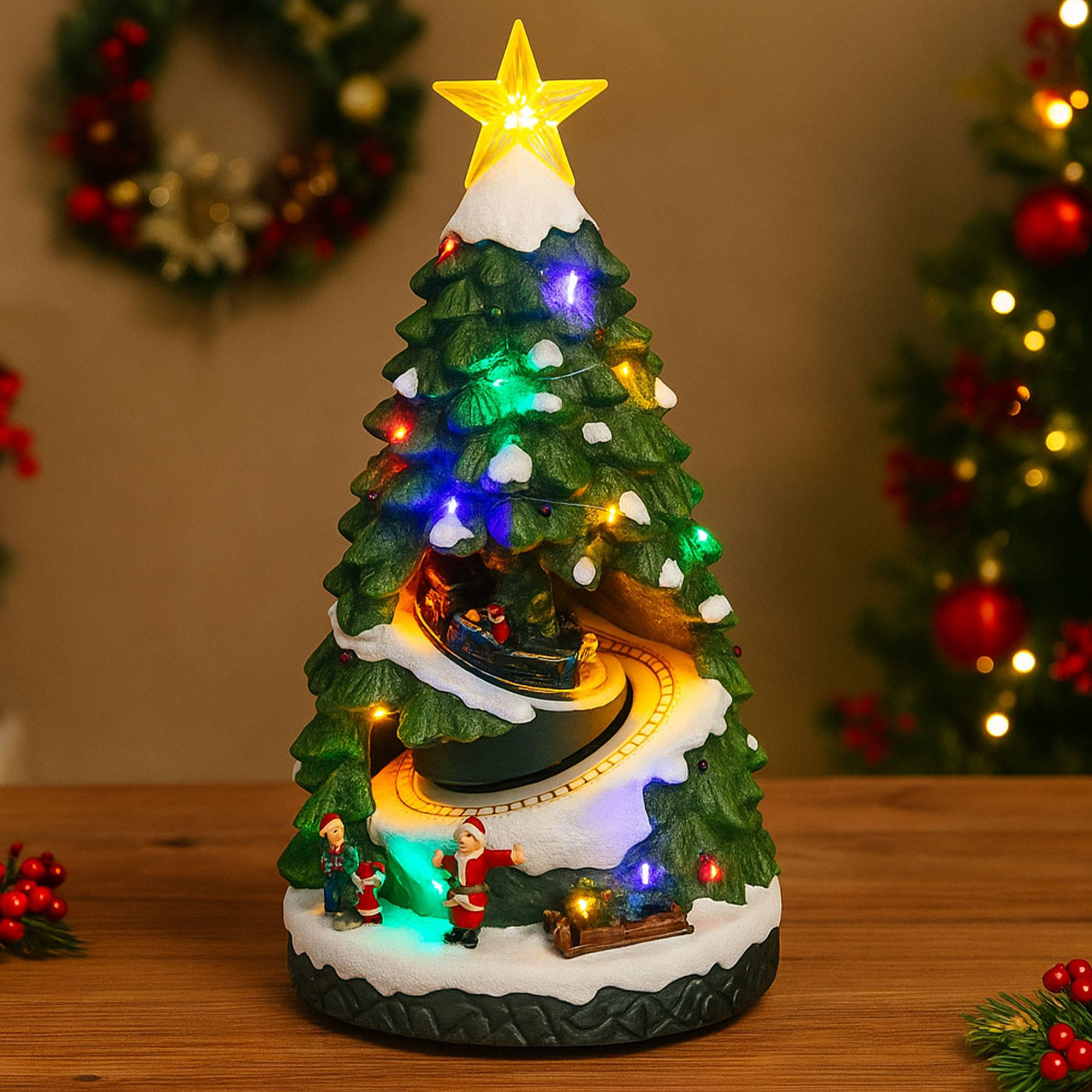 Un árbol de Navidad decorativo con luces, una estrella y un tren dando vueltas en su interior. Papá Noel y niños en la base.