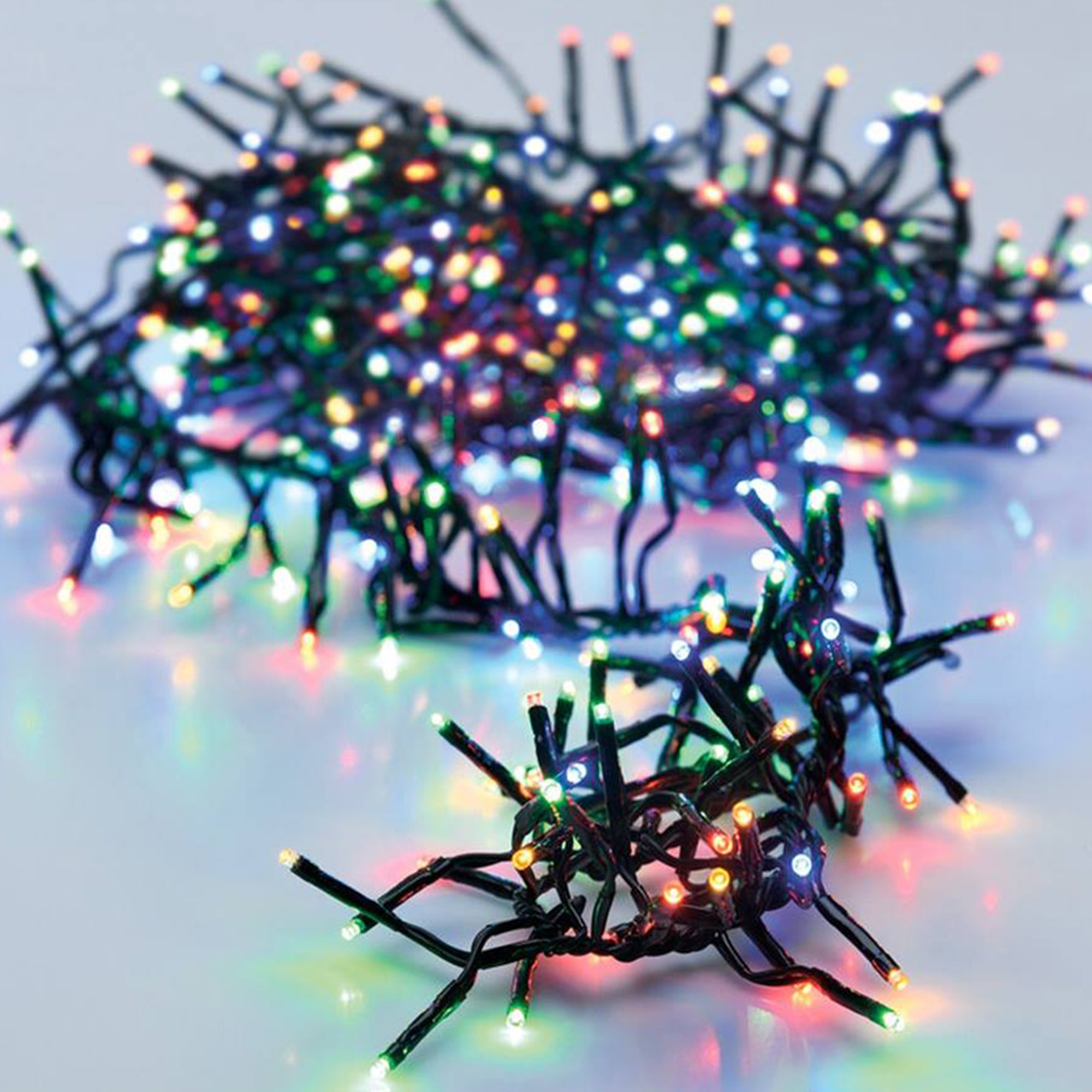 Primer plano de luces navideñas. Muchas luces pequeñas y coloridas en cables oscuros. Algunas luces están enfocadas, otras no.