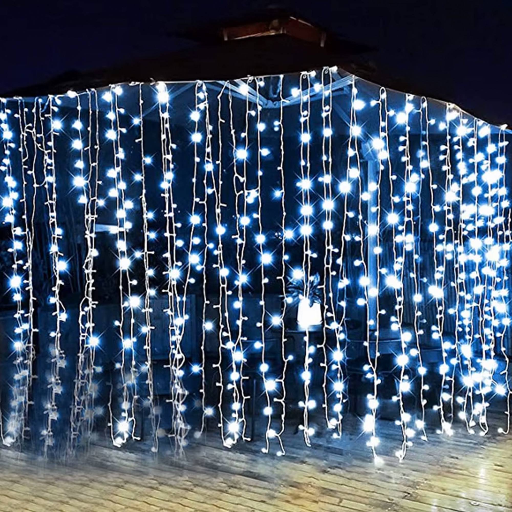 Luces de cadena con luces azules brillantes que cuelgan de una estructura. El fondo es un cielo nocturno oscuro.