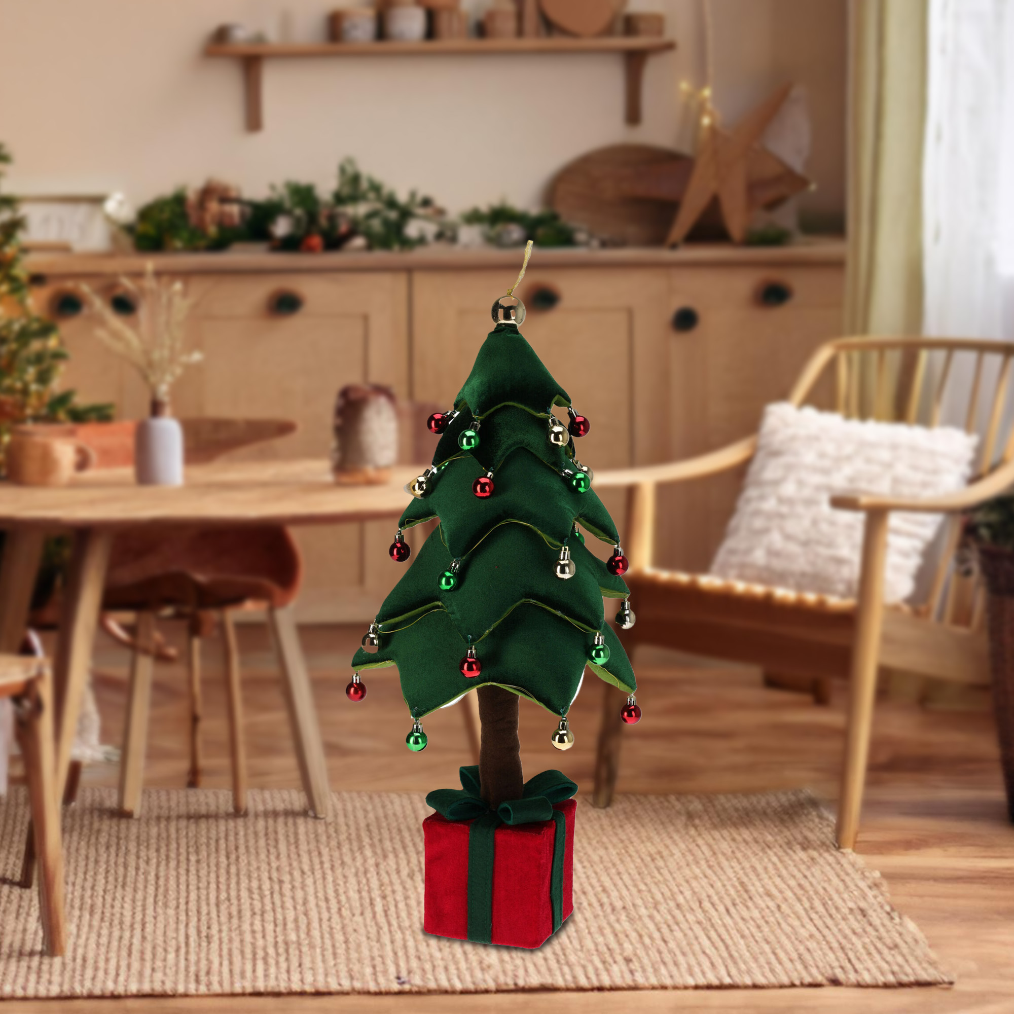 Un árbol de Navidad verde con adornos rojos y dorados sobre una caja de regalo roja. Hay una silla y una mesa de madera en el fondo.