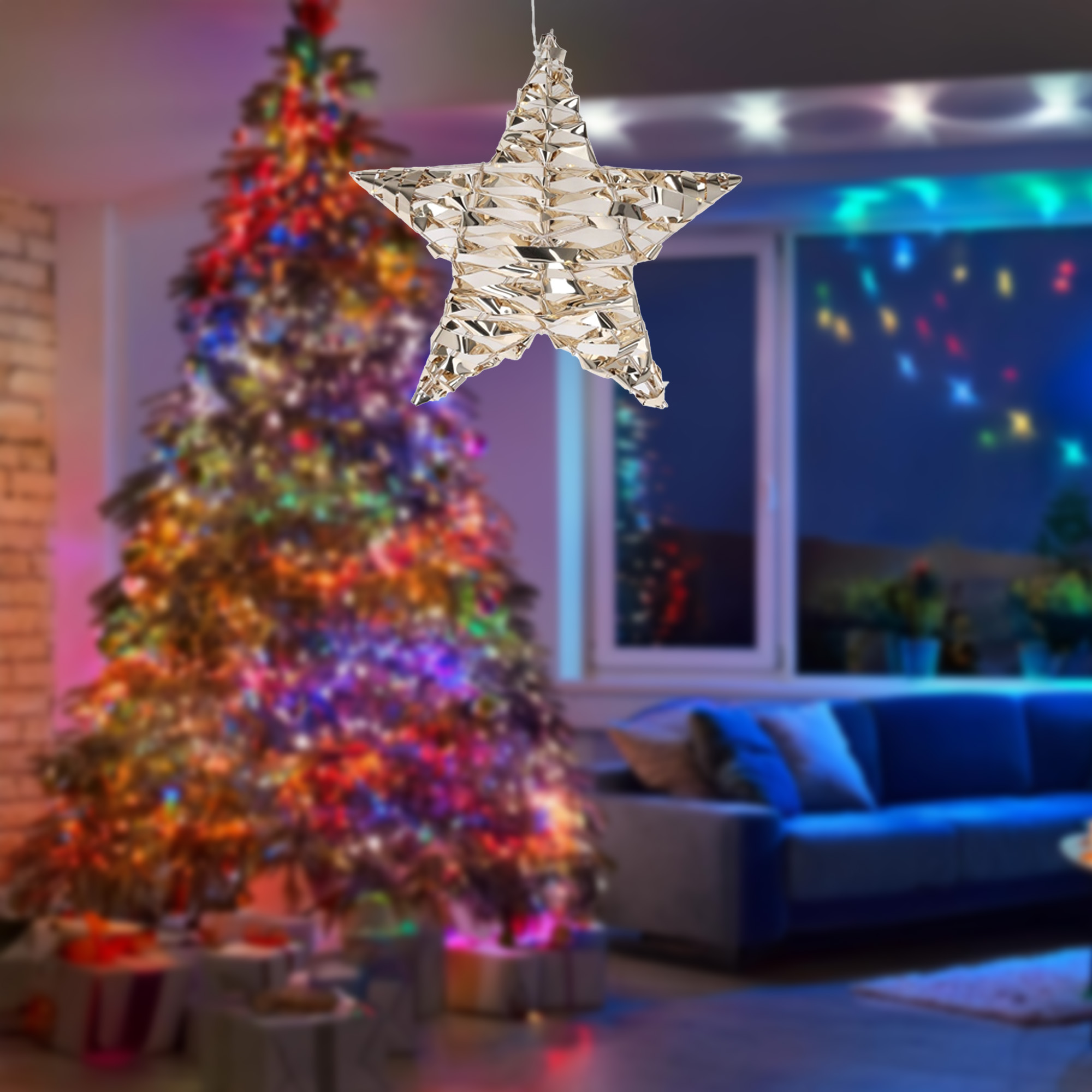 Una estrella dorada cuelga frente a un árbol de Navidad decorado. Debajo hay regalos. Un sofá está en el fondo.