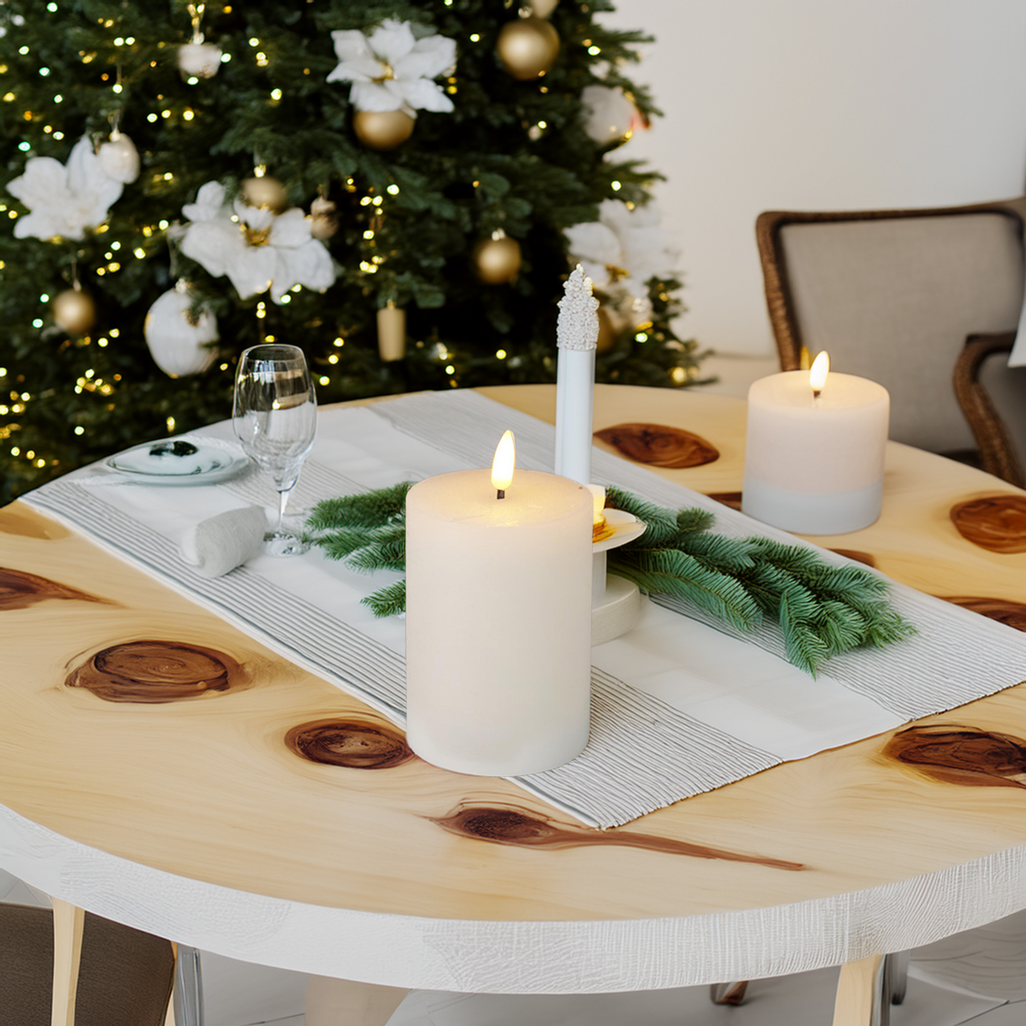 Una mesa redonda de madera preparada para Navidad con velas encendidas y un árbol de Navidad decorado al fondo.