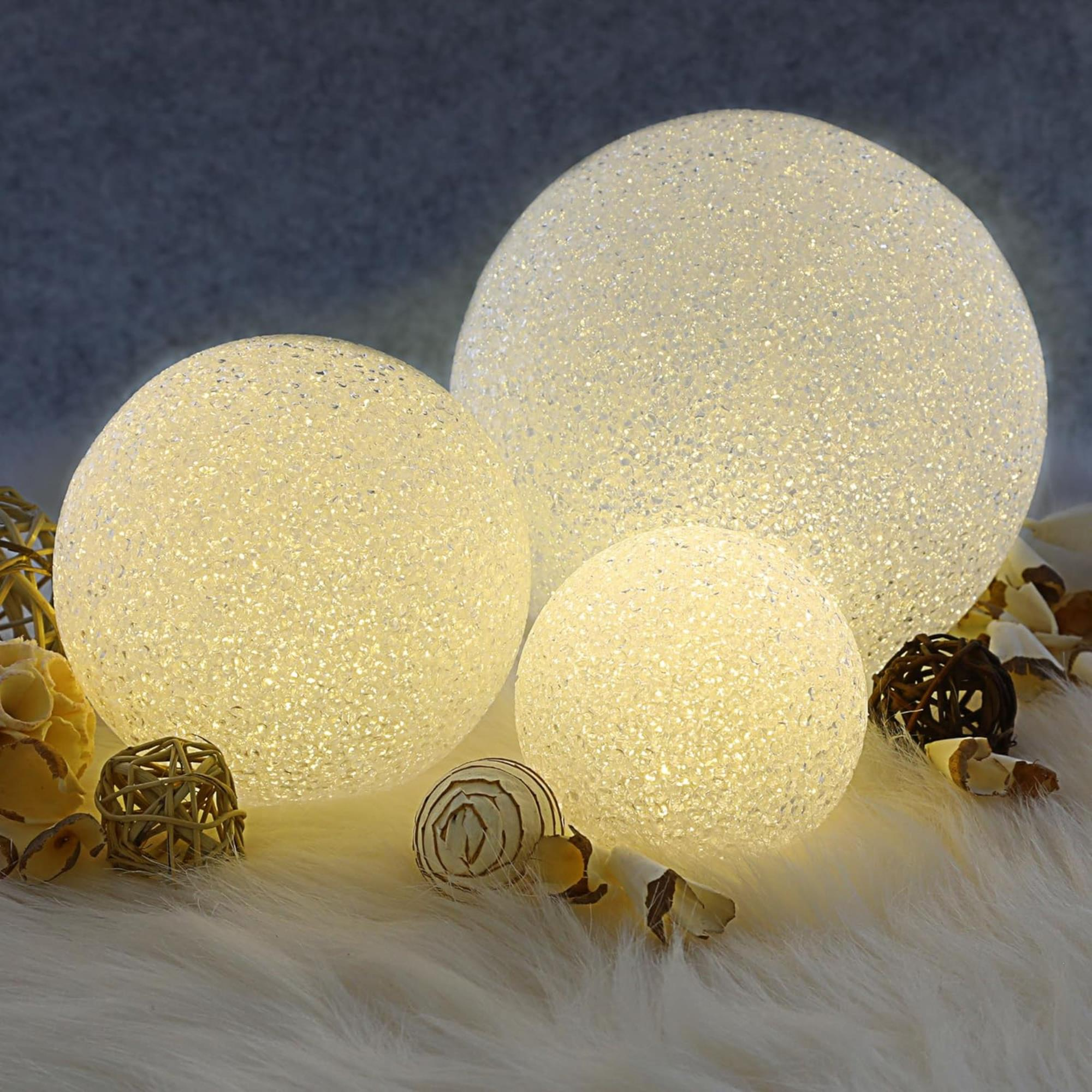 Tres esferas brillantes sobre una superficie peluda con elementos decorativos. El fondo es un degradado de azul a blanco.