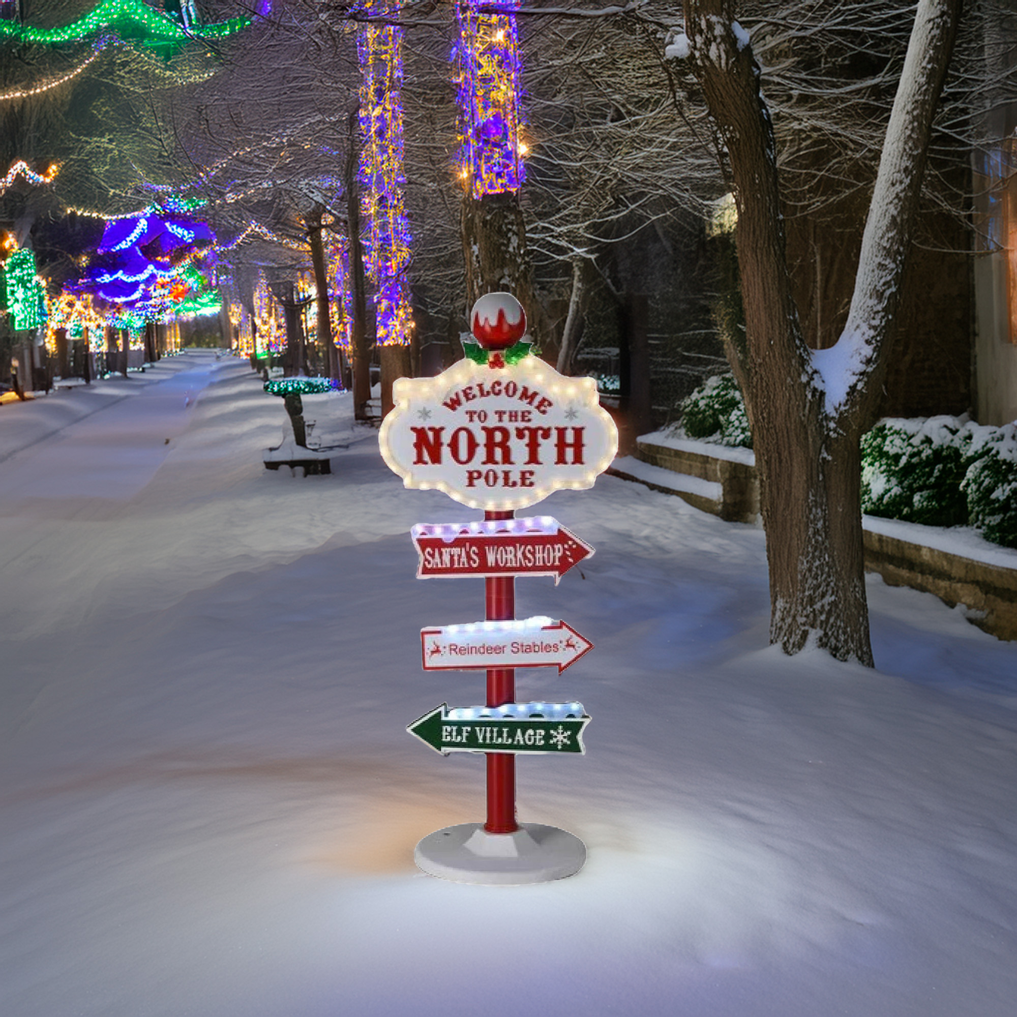 Un letrero da la bienvenida al Polo Norte, con indicaciones. La nieve cubre el suelo. Los árboles están iluminados con luces navideñas de colores.
