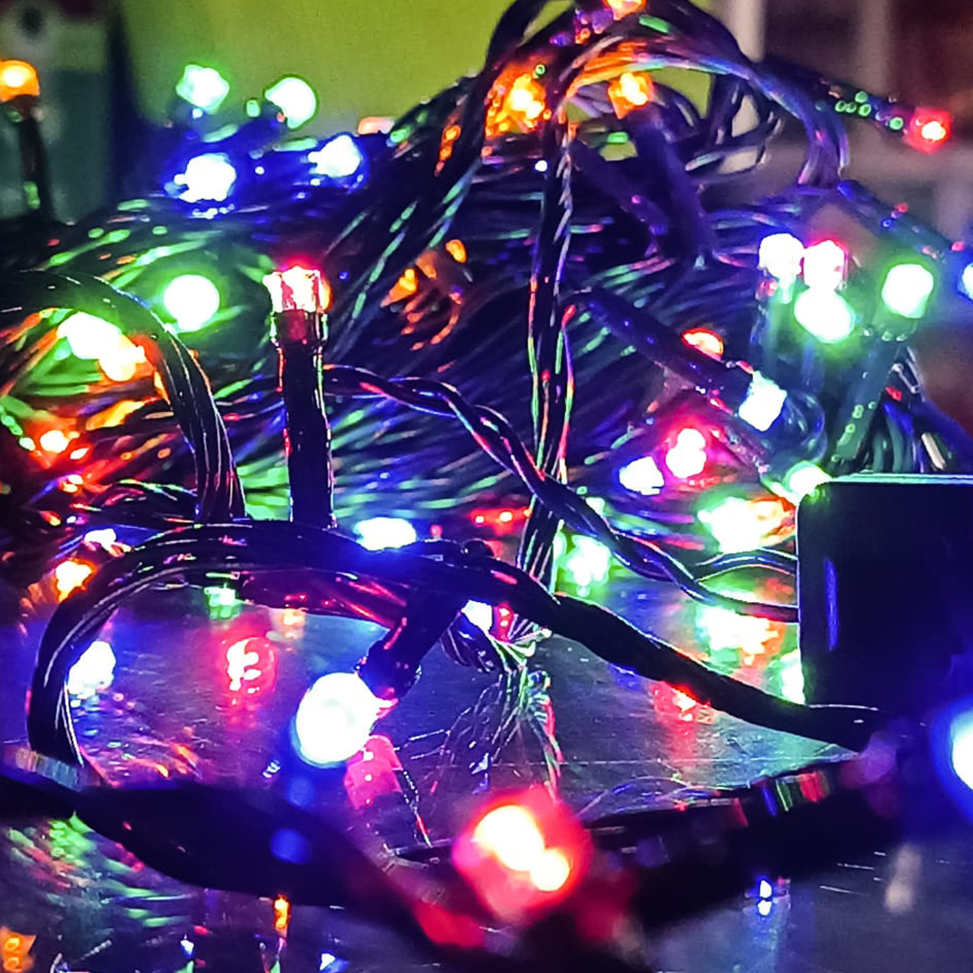 Primer plano de luces de cadena enredadas con LED rojos, verdes, azules y amarillos. El fondo está borroso.