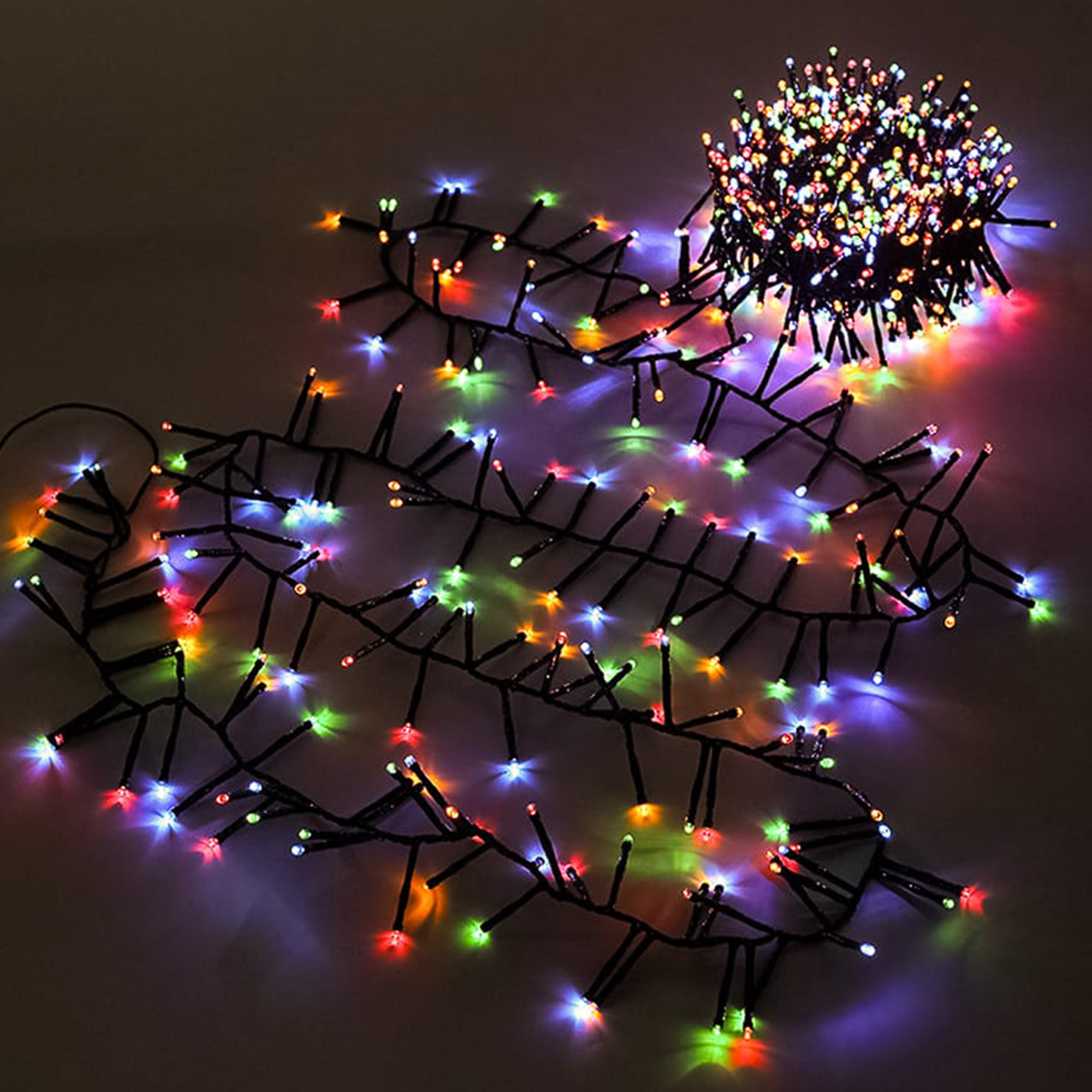 Luces de cadena con múltiples LED pequeños y coloridos sobre una superficie oscura. Un grupo de luces y varios hilos.
