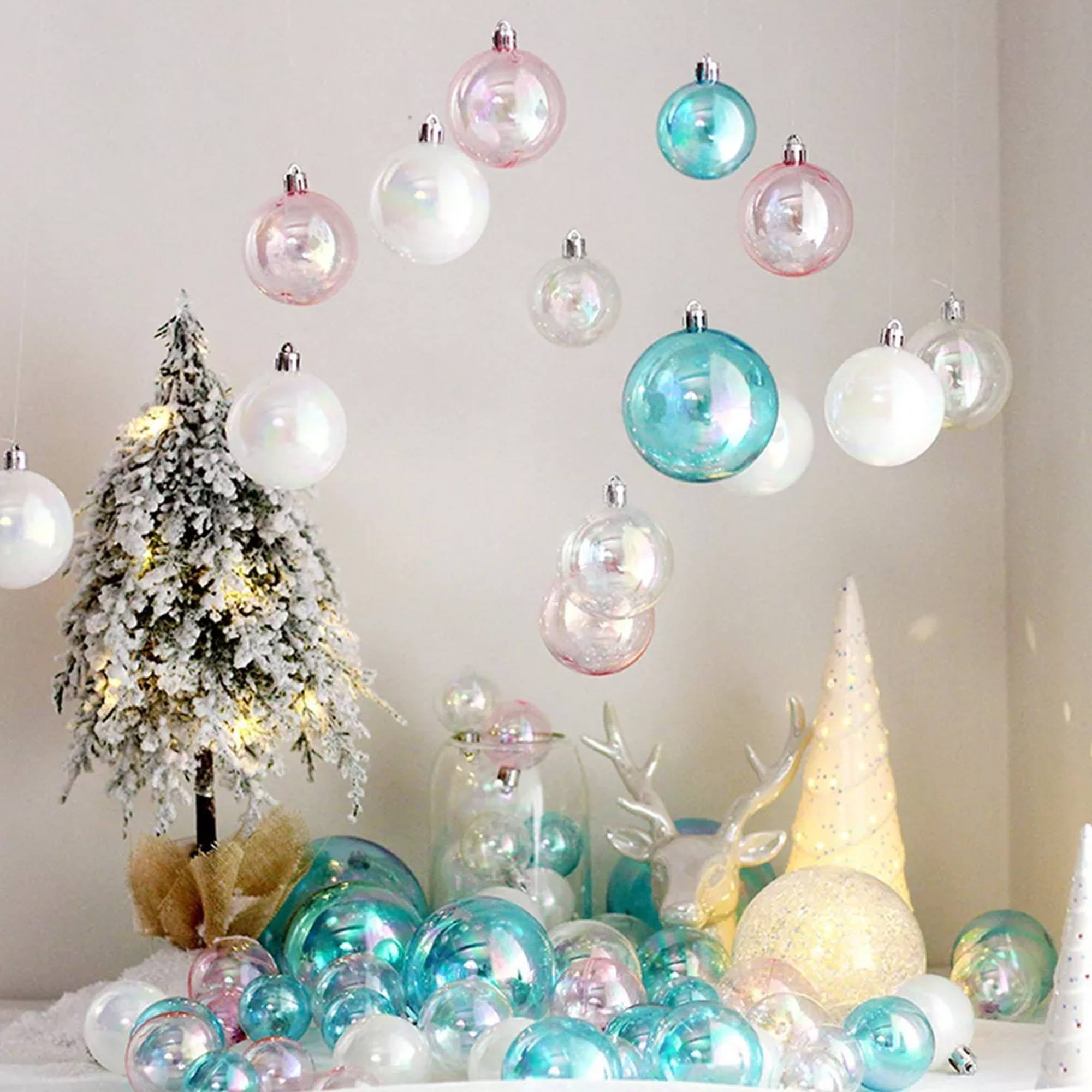 Decoraciones navideñas: bolas de cristal, un arbolito y objetos decorativos. Las bolas son rosas, blancas y turquesas.