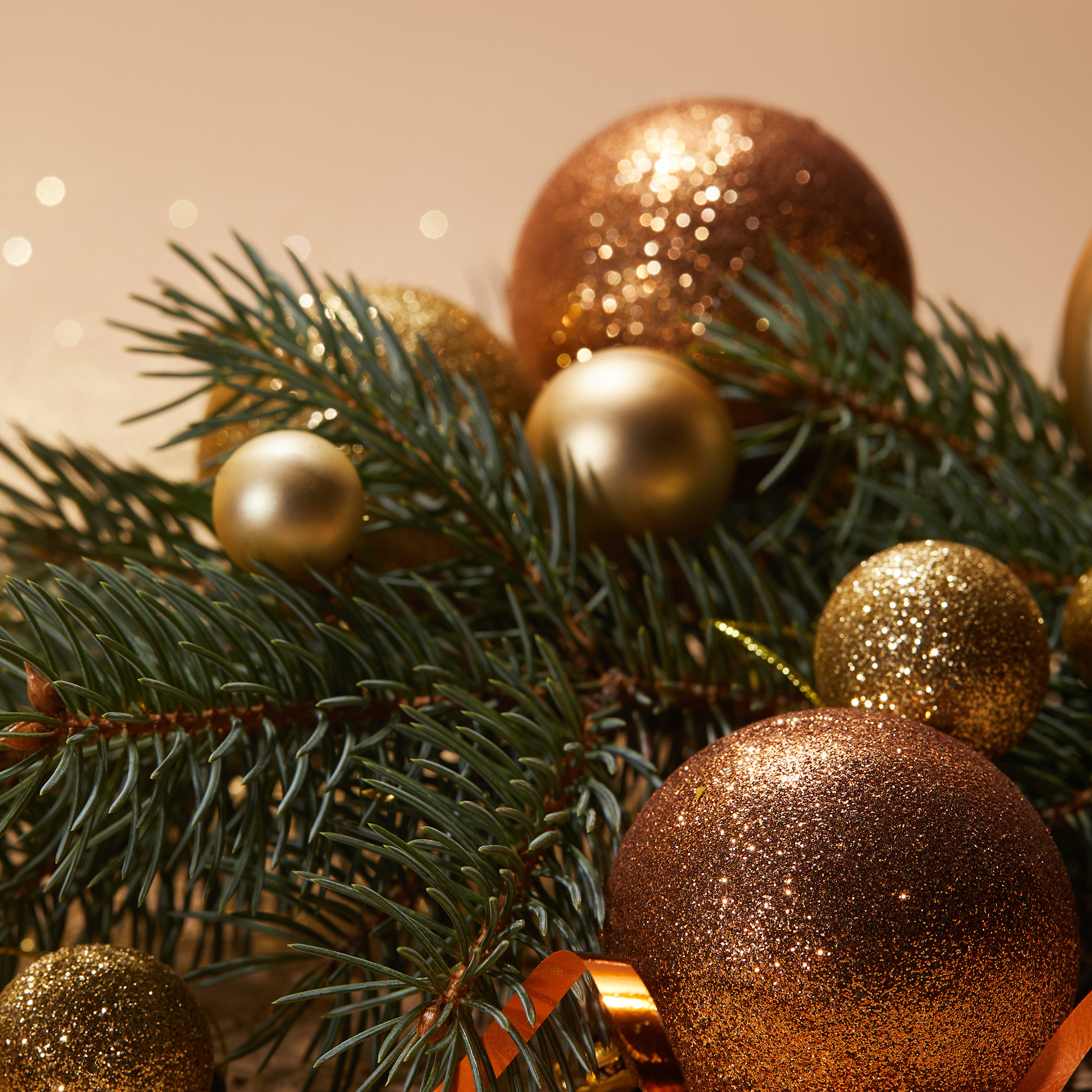 Primer plano de adornos navideños y ramas de pino. Bolas doradas con brillo y acabado liso.