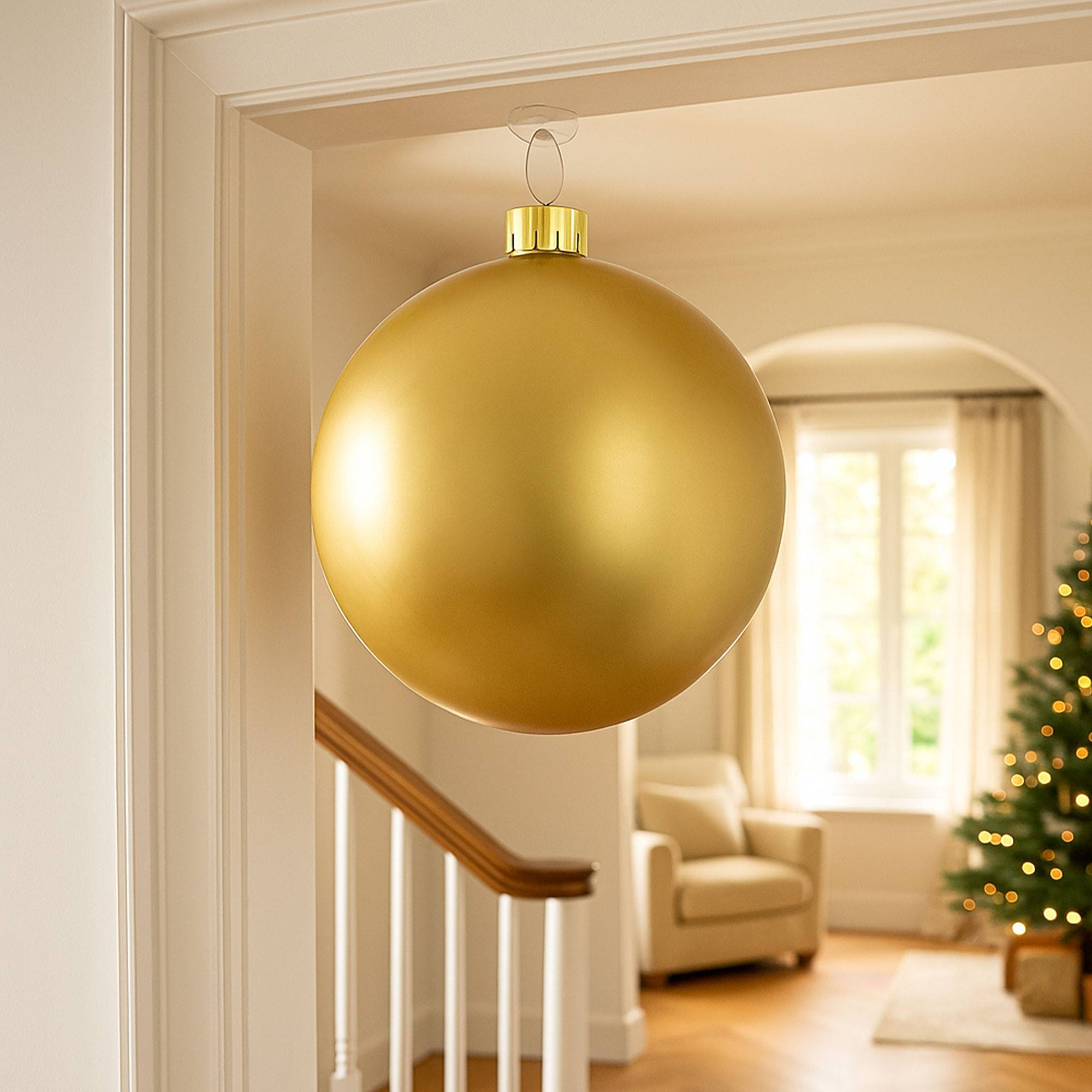 Un gran adorno navideño dorado cuelga en una puerta. Un árbol de Navidad es visible en el fondo.
