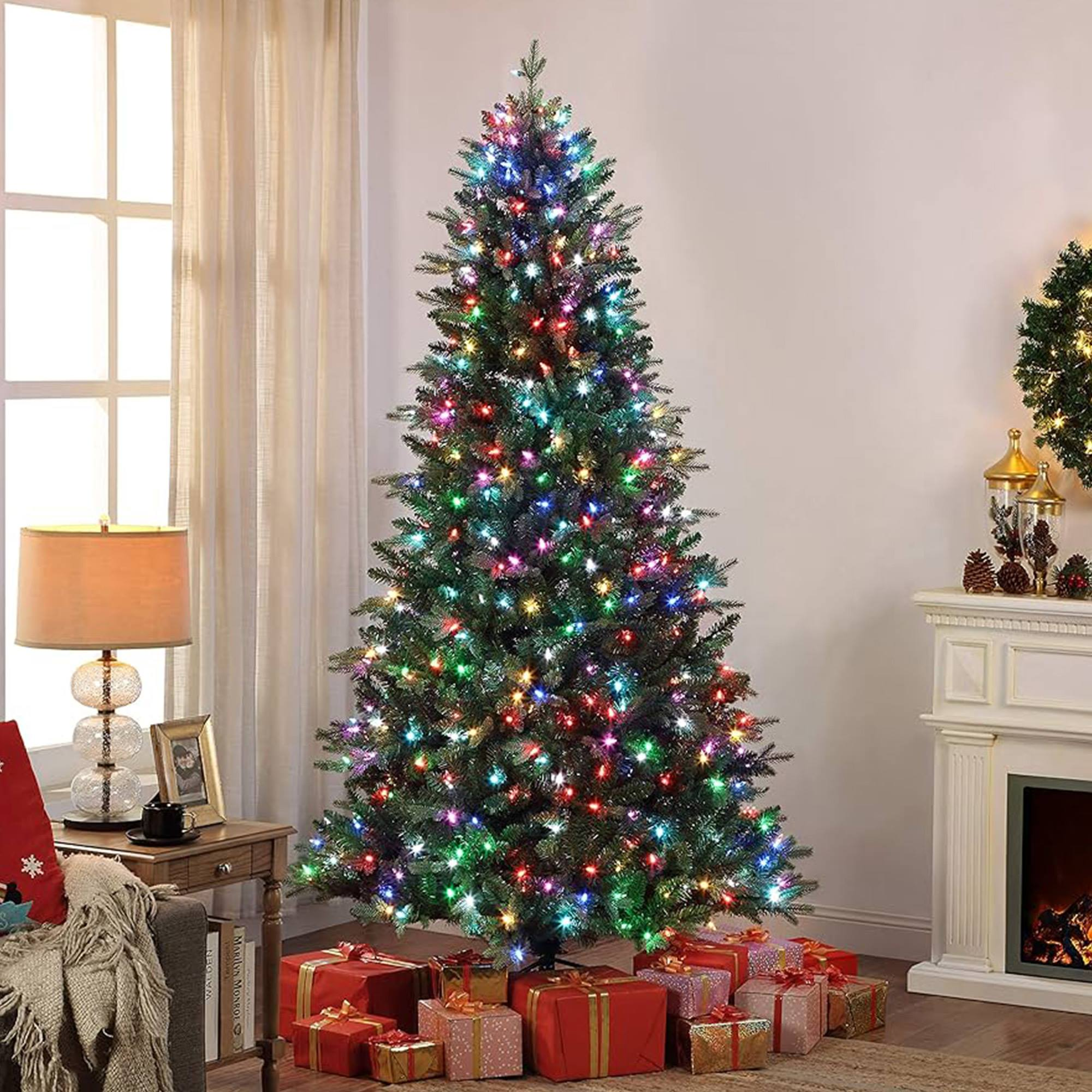 Árbol de Navidad con luces de colores y regalos debajo. Una chimenea y una ventana en el fondo.
