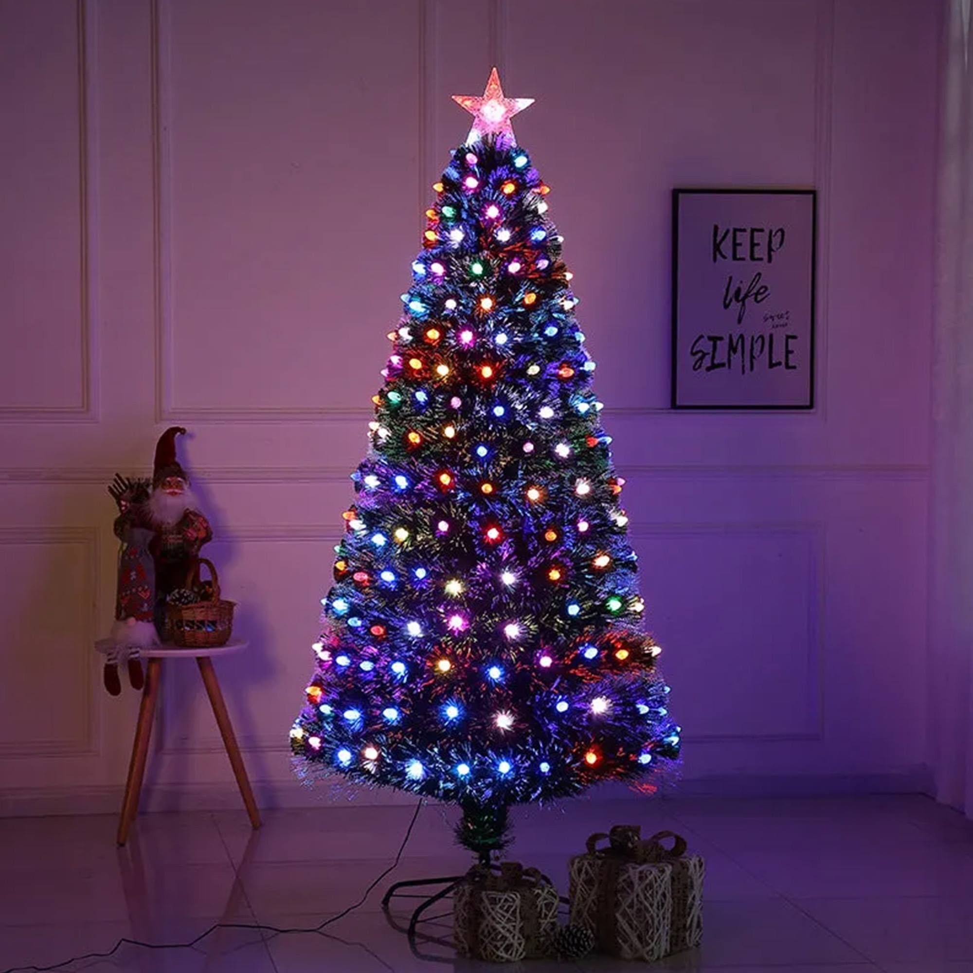 Un árbol de Navidad iluminado con una estrella en la cima. Hay una figura de Papá Noel y regalos.