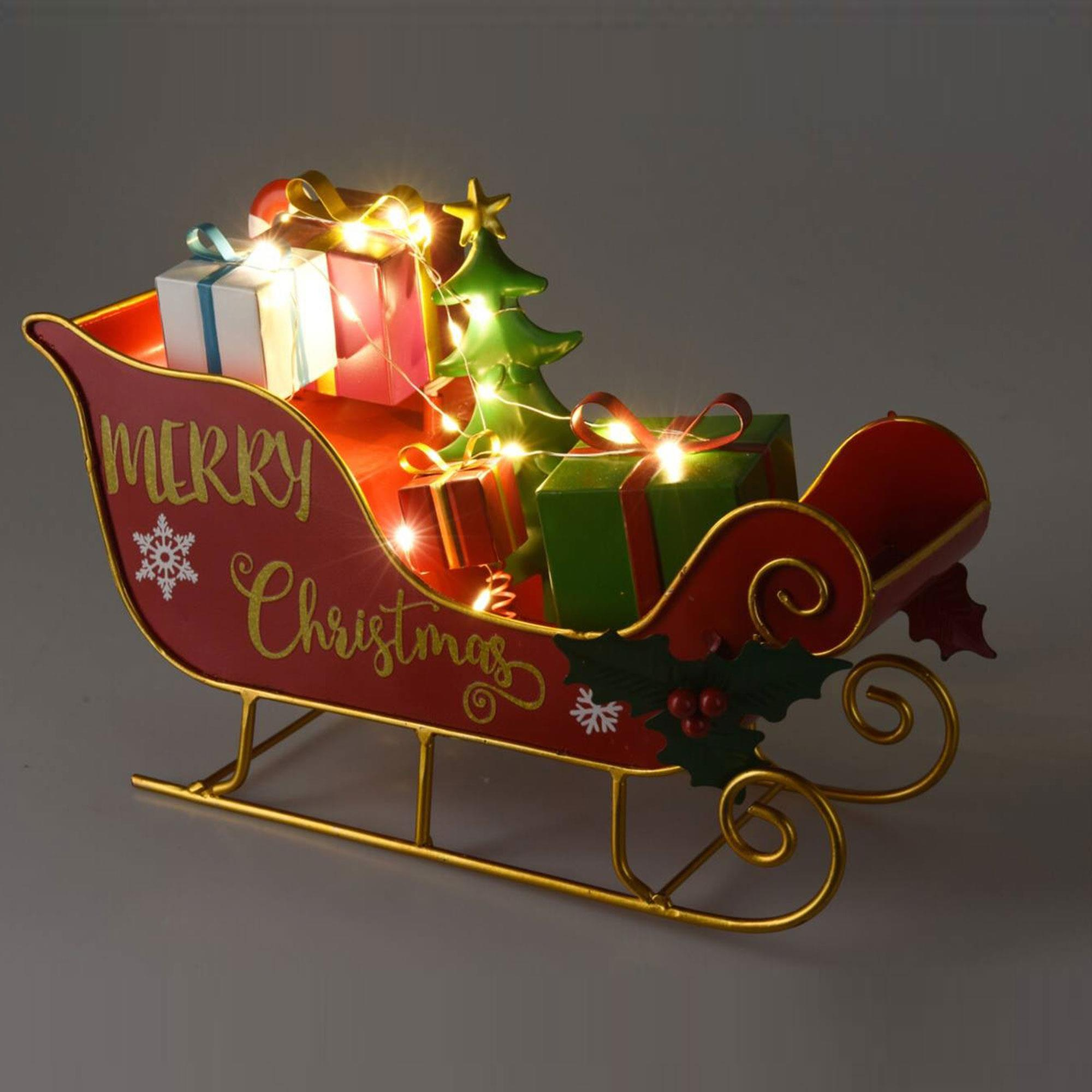 Ein roter Schlitten mit Geschenken, einem Weihnachtsbaum und Lichtern. Auf der Seite steht 'Merry Christmas'. Goldakzente.