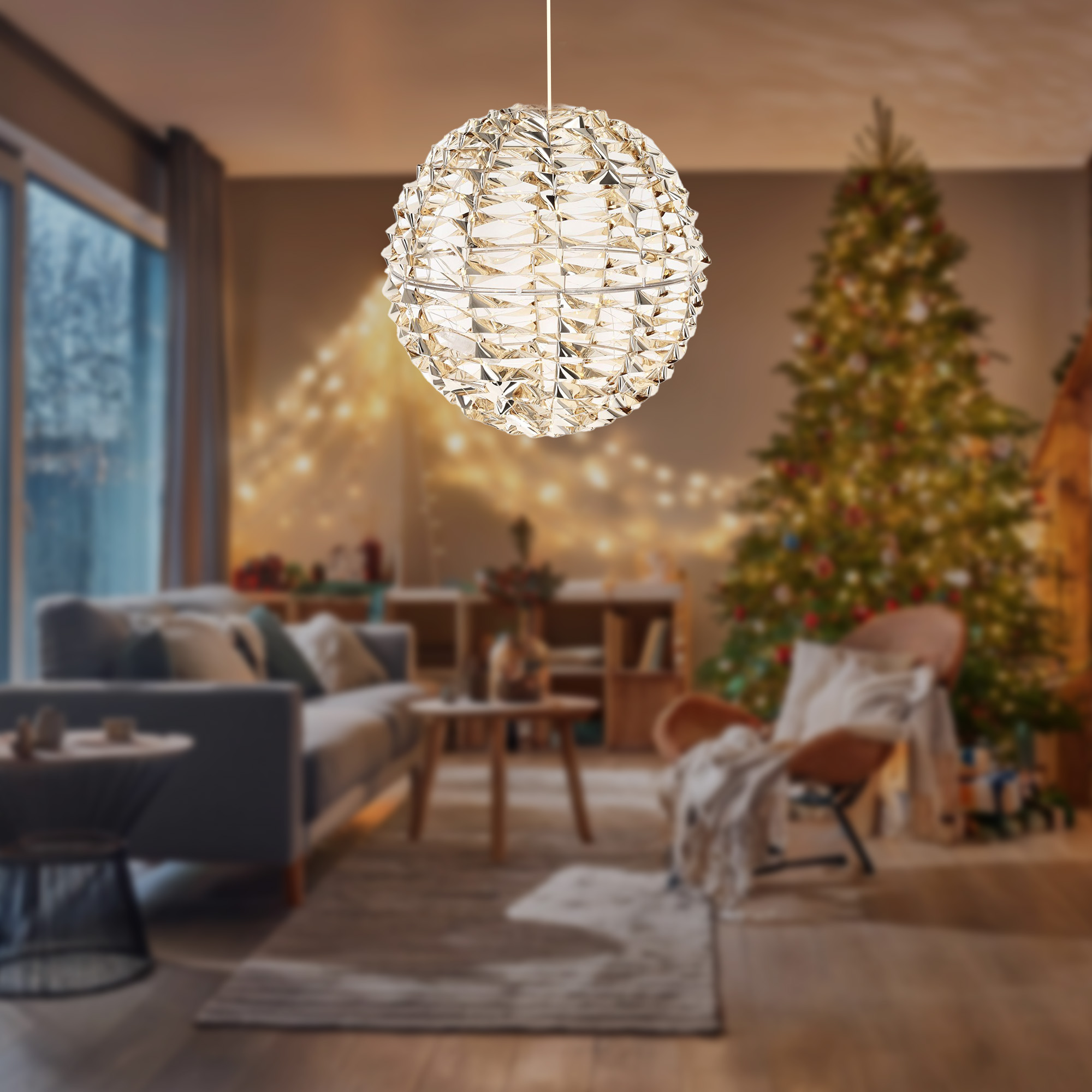 Una esfera decorativa iluminada cuelga en una acogedora sala de estar. Un árbol de Navidad y un sofá están al fondo.