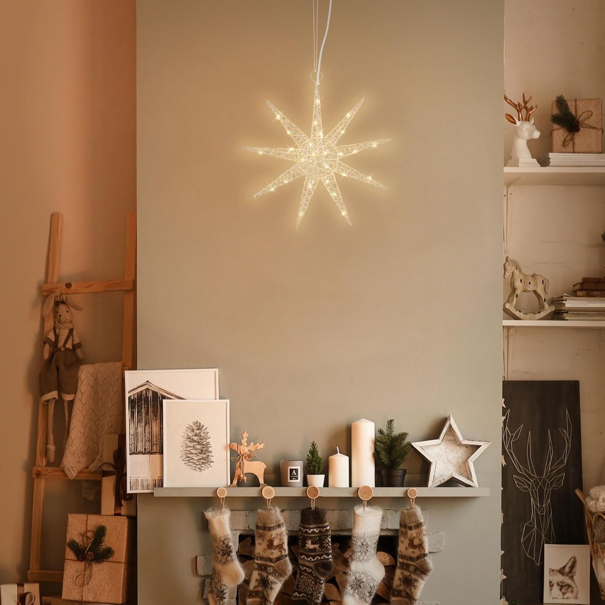 Una luz navideña en forma de estrella cuelga sobre una chimenea decorada con medias, velas y arte.