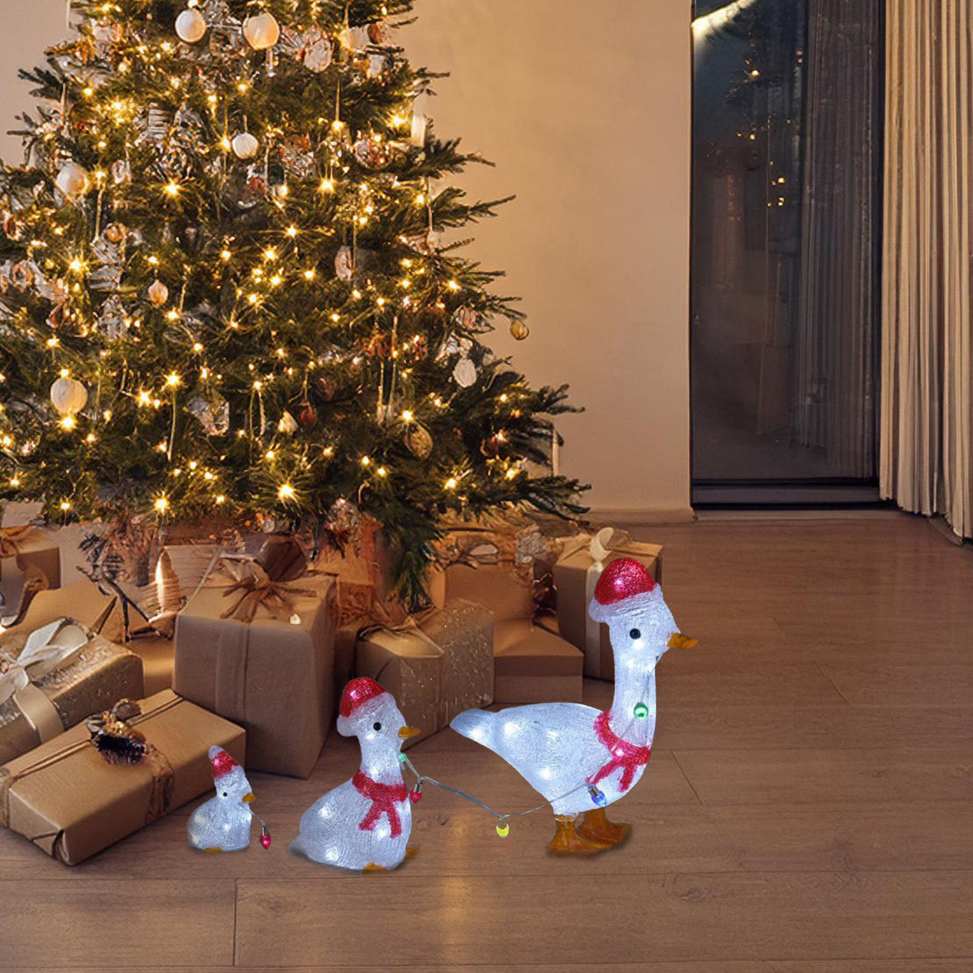 Una escena navideña con decoraciones de gansos iluminados con gorros de Papá Noel, un árbol decorado y regalos envueltos.