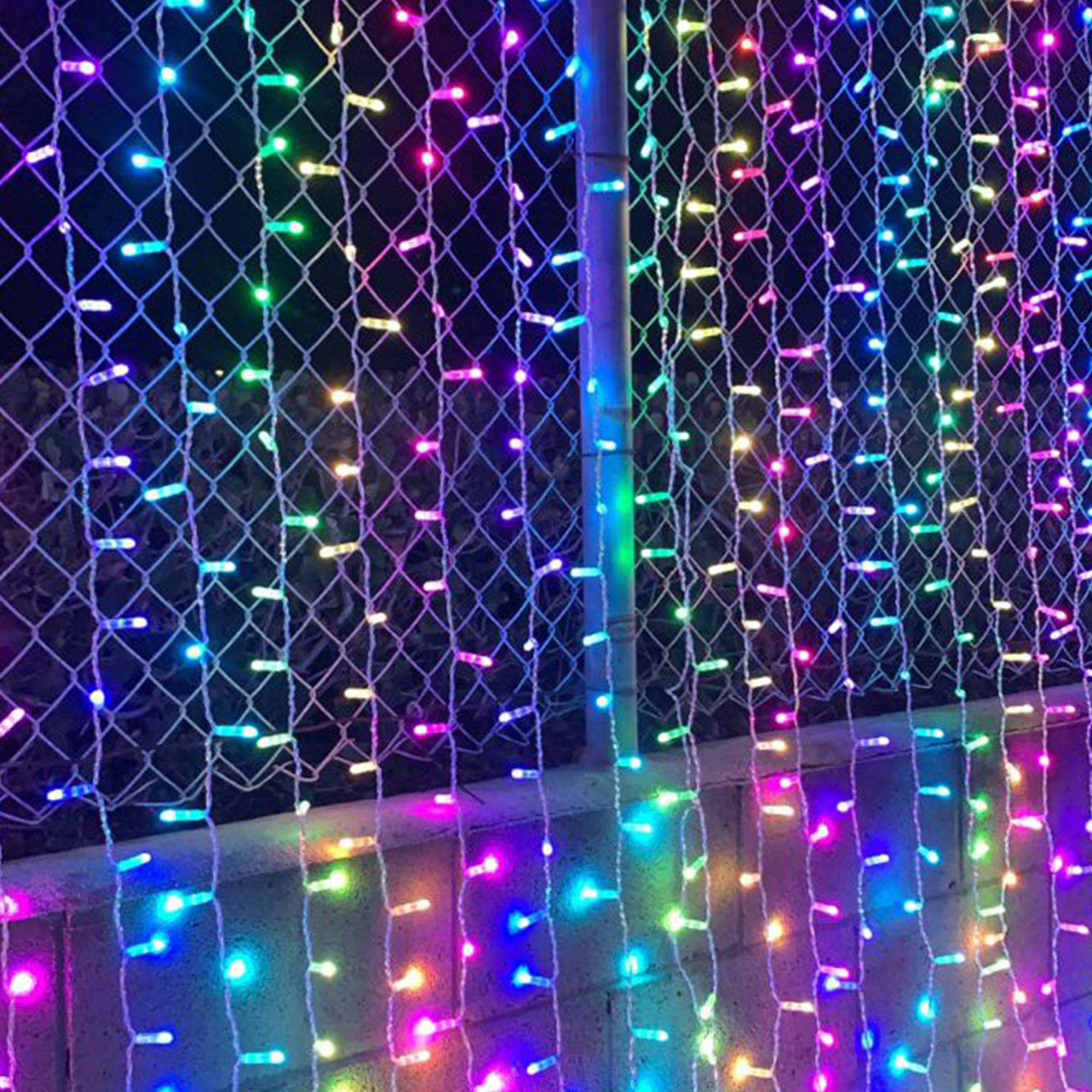 Una valla adornada con hileras de luces de colores, creando una exhibición vibrante y festiva.
