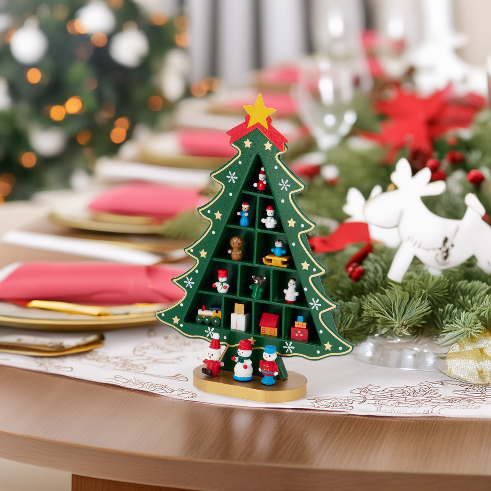 Un estante de árbol de Navidad con figuras en miniatura está en una mesa para la cena navideña. Se ven decoraciones y comida.