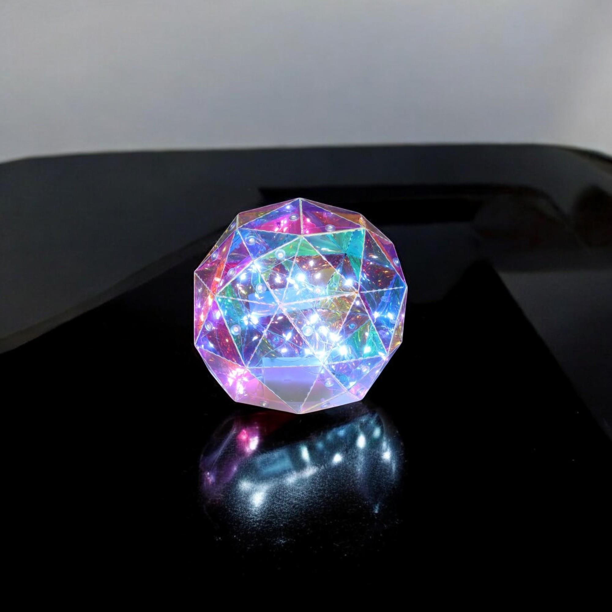 Una esfera facetada y brillante sobre una superficie negra brillante. La esfera refleja luz multicolor, con fondo blanco.