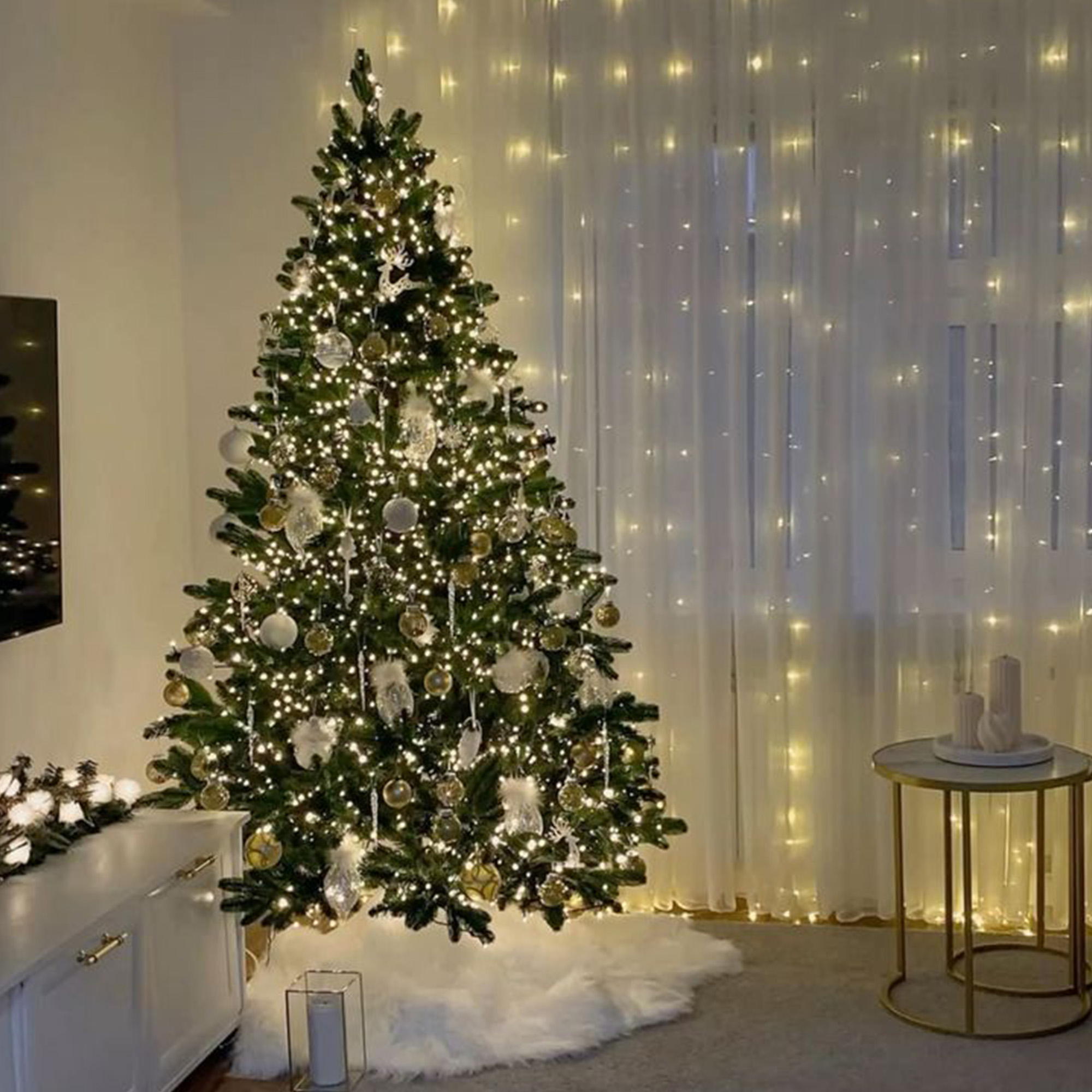 Árbol de Navidad con adornos y luces, junto a una ventana con luces y una mesita.