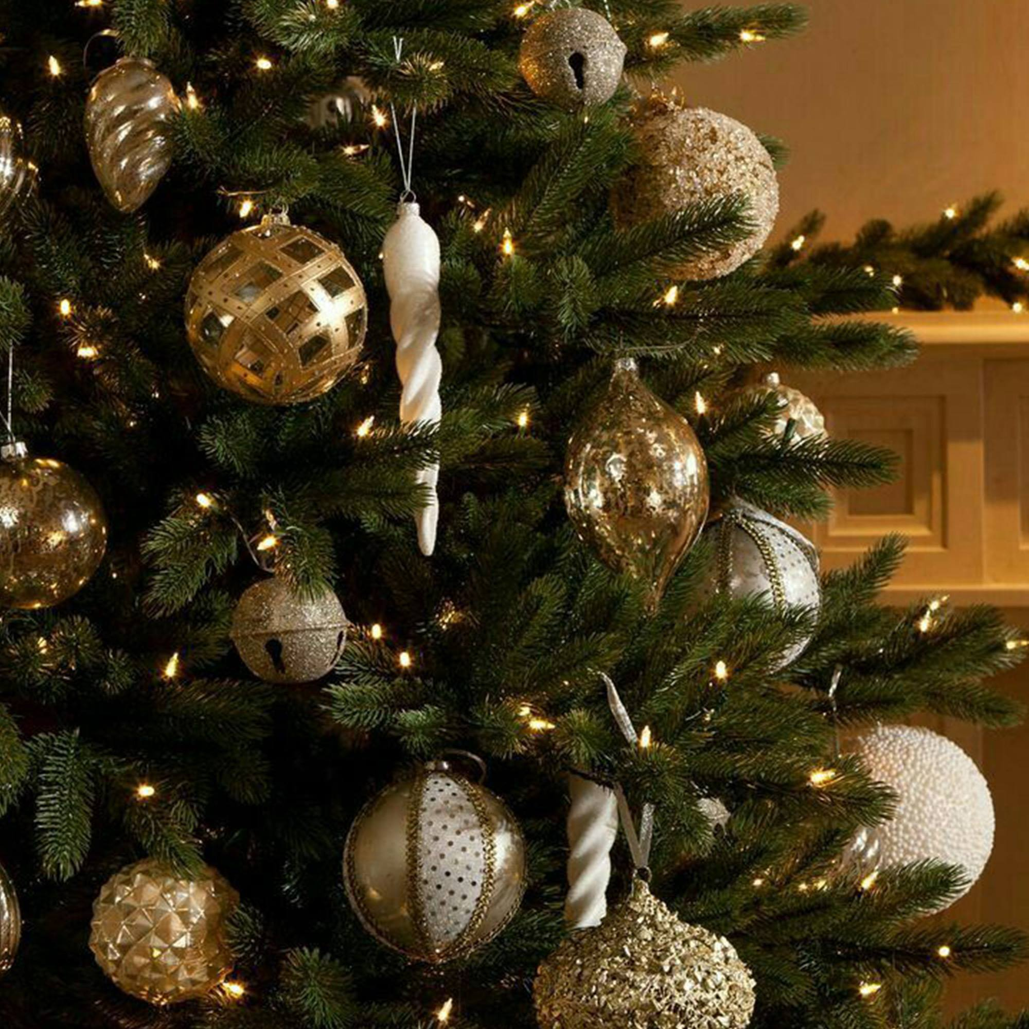 Un árbol de Navidad decorado con adornos dorados y blancos, luces y ramas verdes.