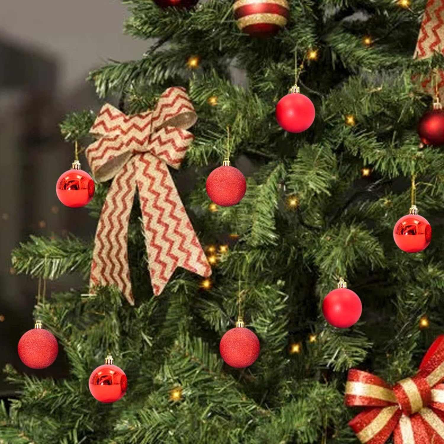 Un árbol de Navidad decorado con adornos rojos, un lazo y luces doradas. El fondo está borroso.
