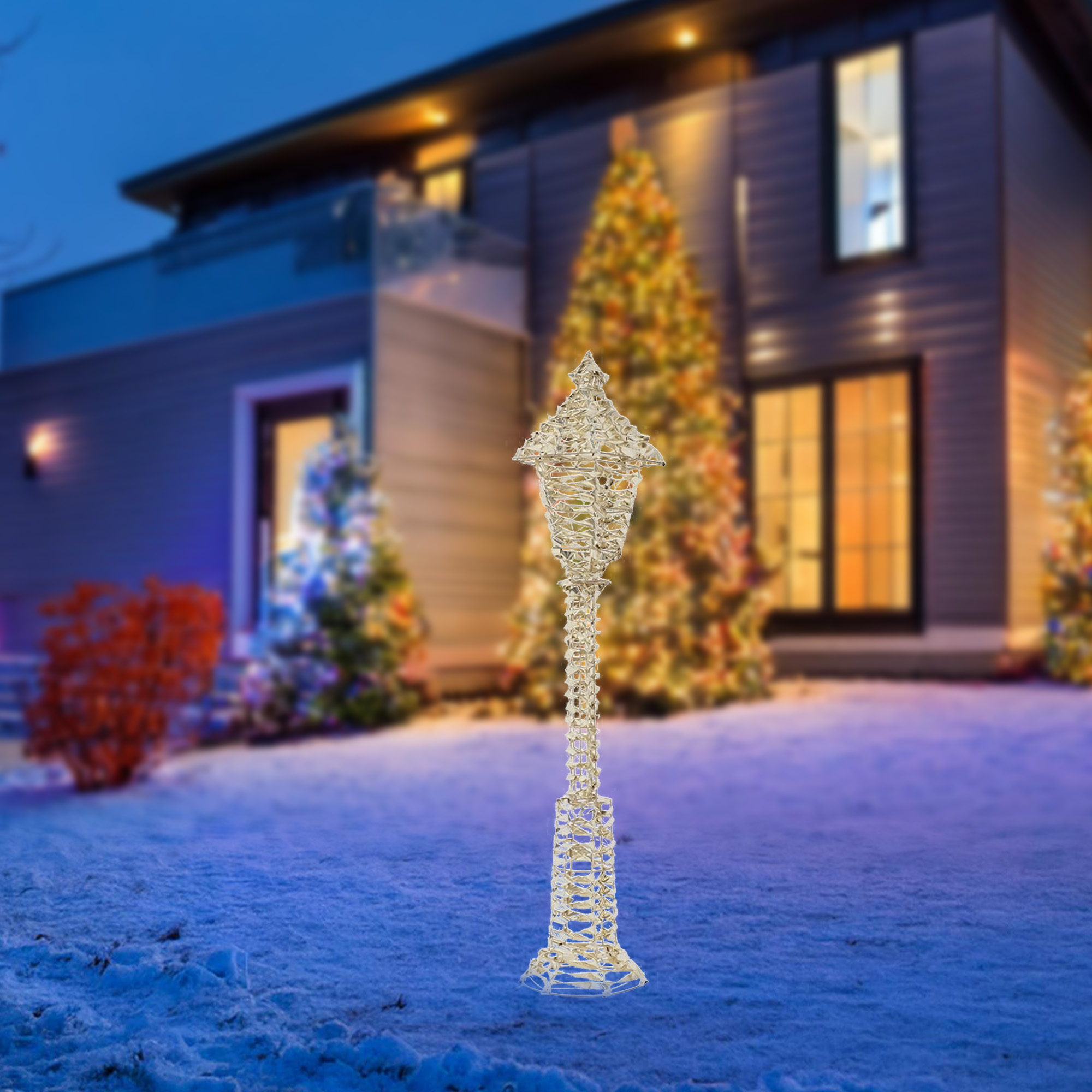 Un farol dorado decorativo frente a una casa. Los árboles de Navidad están al fondo.