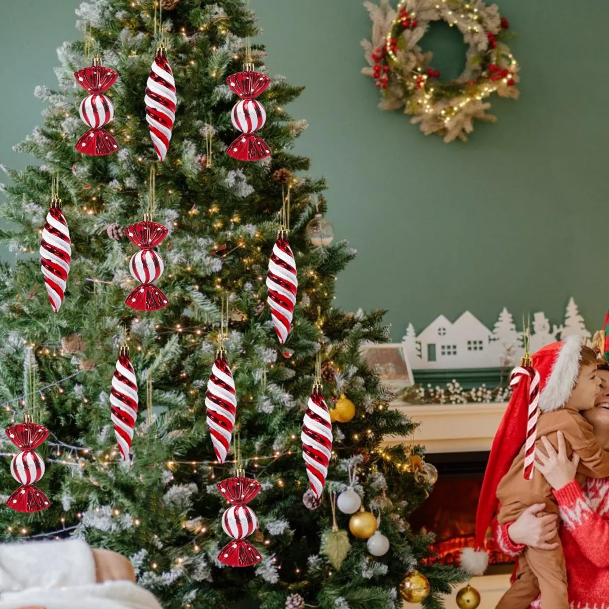 Árbol de Navidad con adornos rojos y blancos. Una mujer abraza a un niño con gorro de Papá Noel. Una corona cuelga de la pared.