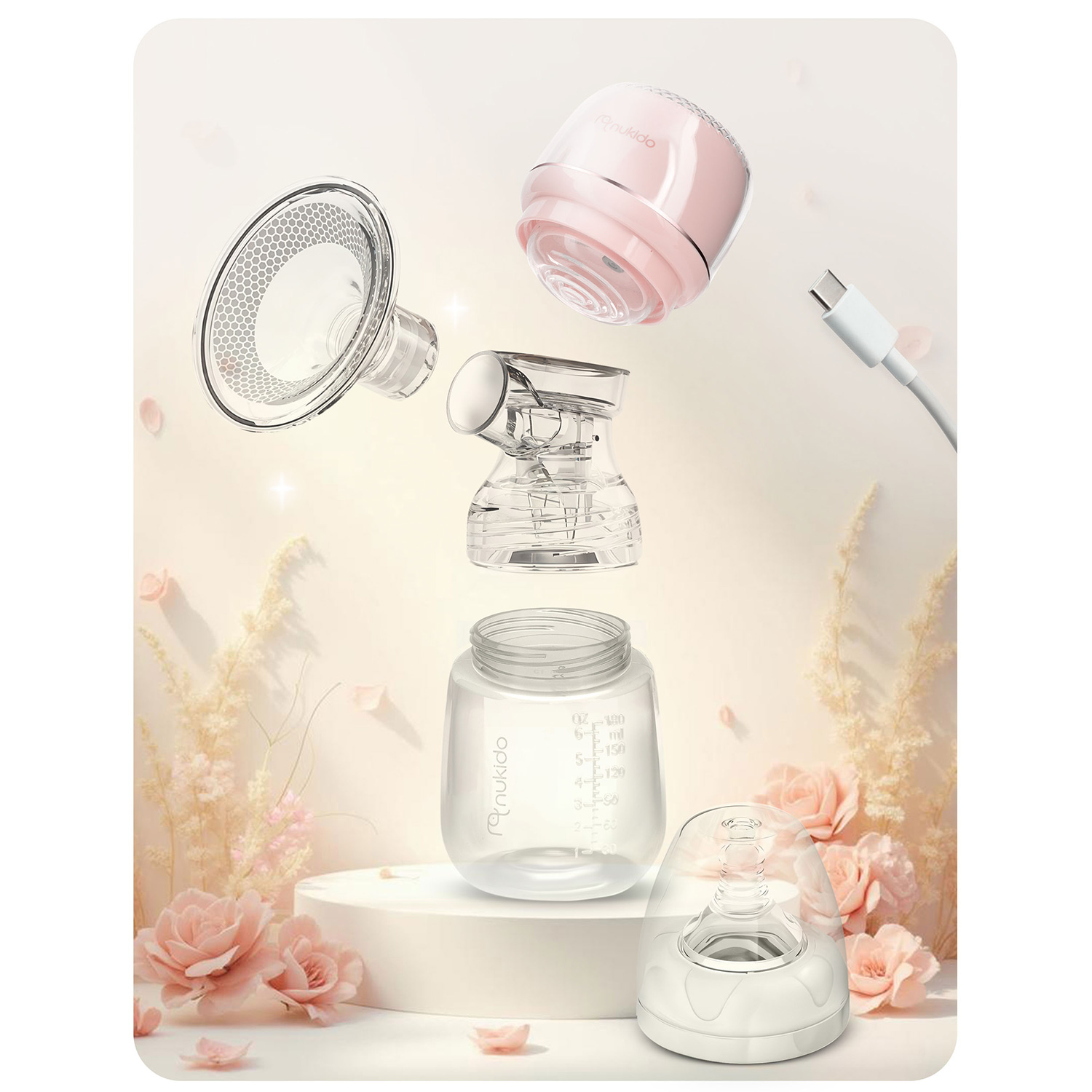 Widok rozstrzelony różowo-białej pompy do piersi z elementami, butelką, kablem USB-C i dekoracjami kwiatowymi.