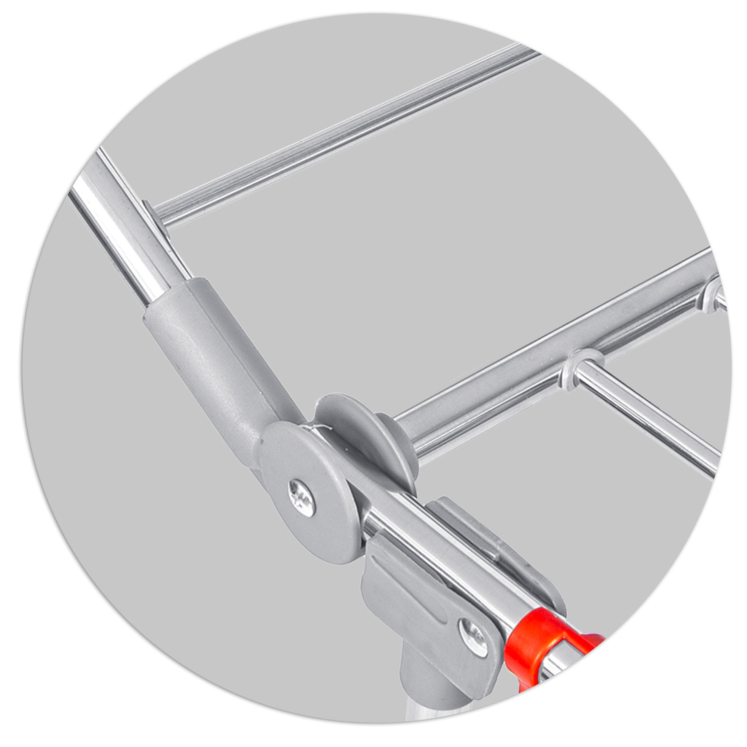 Zbliżenie metalowego, składanego przedmiotu. Widoczne są srebrne metalowe pręty i szare plastikowe połączenia. Czerwony uchwyt znajduje się na dole.