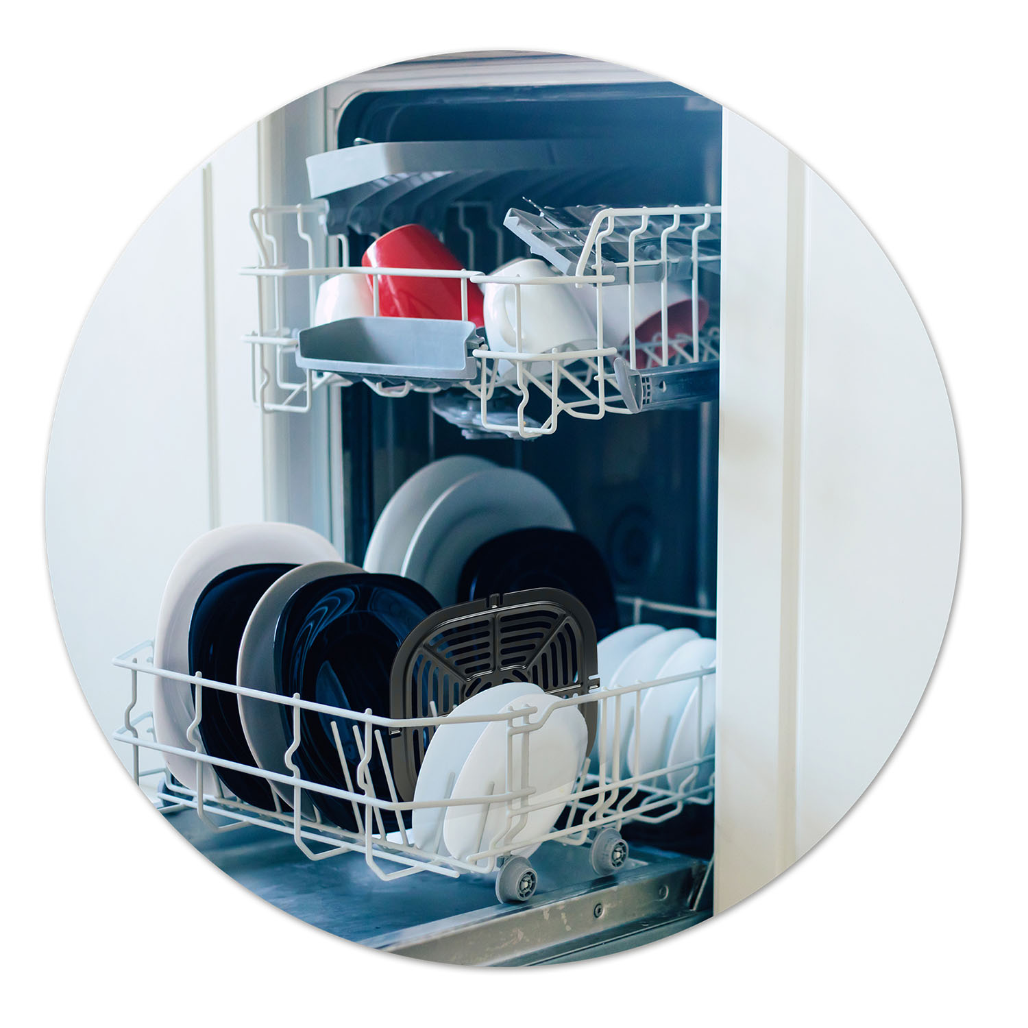 Zmywarka jest otwarta, wypełniona naczyniami. Widoczne są talerze, miski i kubki. Górny kosz zawiera czerwone kubki. Dolny kosz ma talerze.