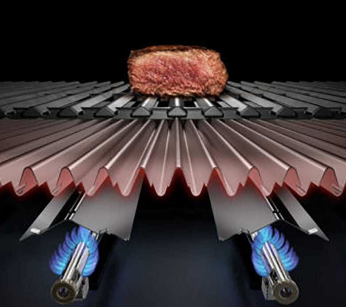 Una bistecca sulla griglia. La griglia ha griglie metalliche e un design rosso ondulato sotto. Le fiamme blu sono visibili.