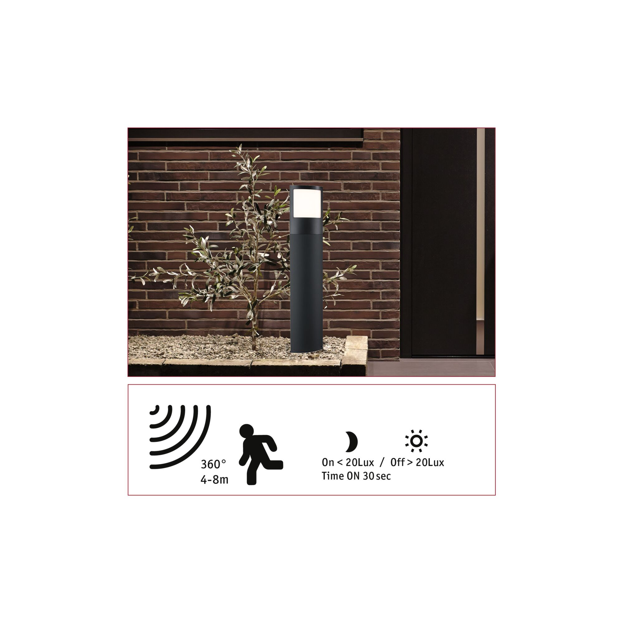 Czarna, cylindryczna lampa zewnętrzna stoi przed ceglanym murem, obok rośnie mały krzew. Drzwi po prawej, ikony czujników na dole.
