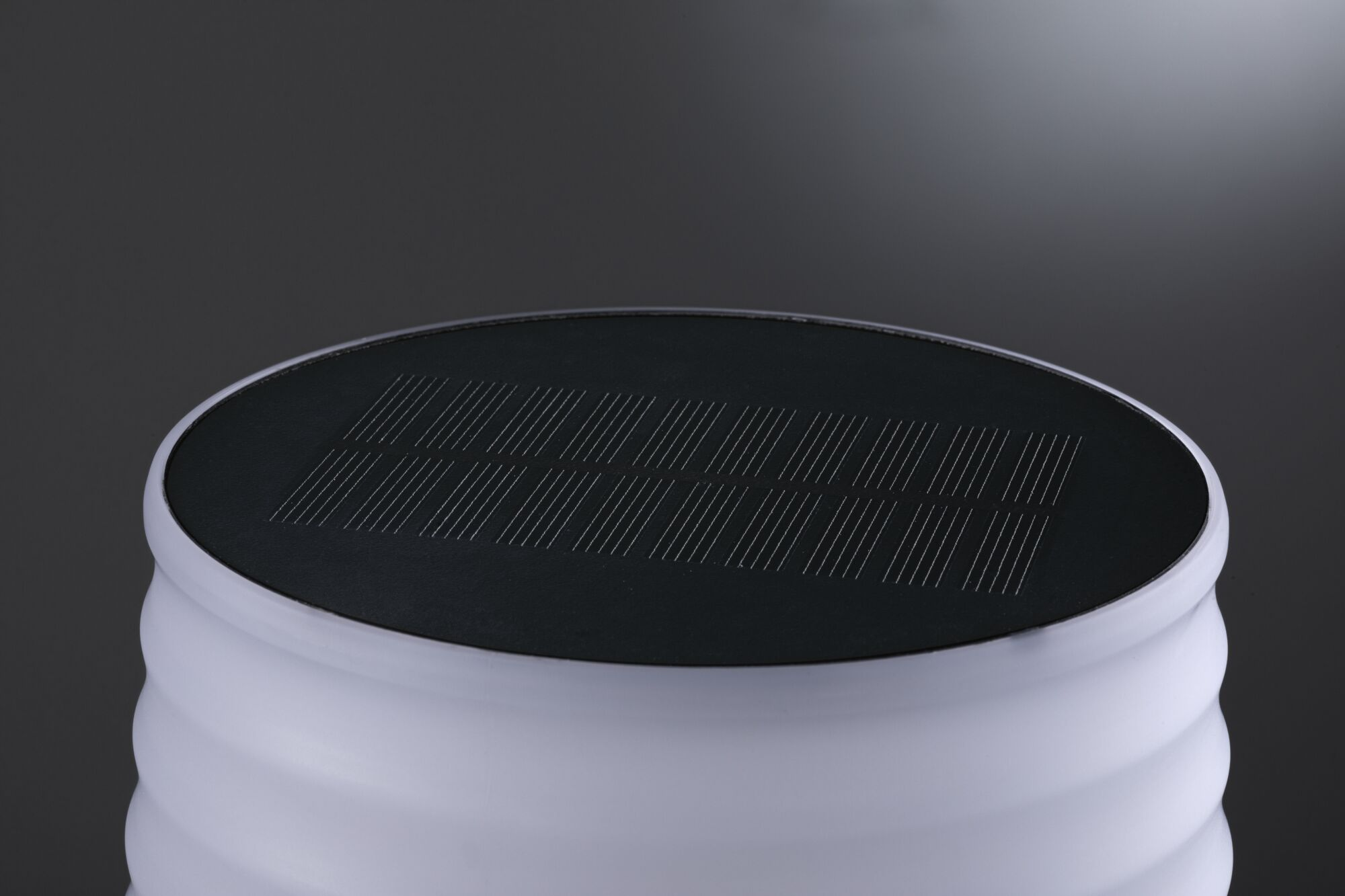 Cylindryczna biała lampa z czarnym panelem słonecznym na górze. Tło to gradient od szarego do czarnego.