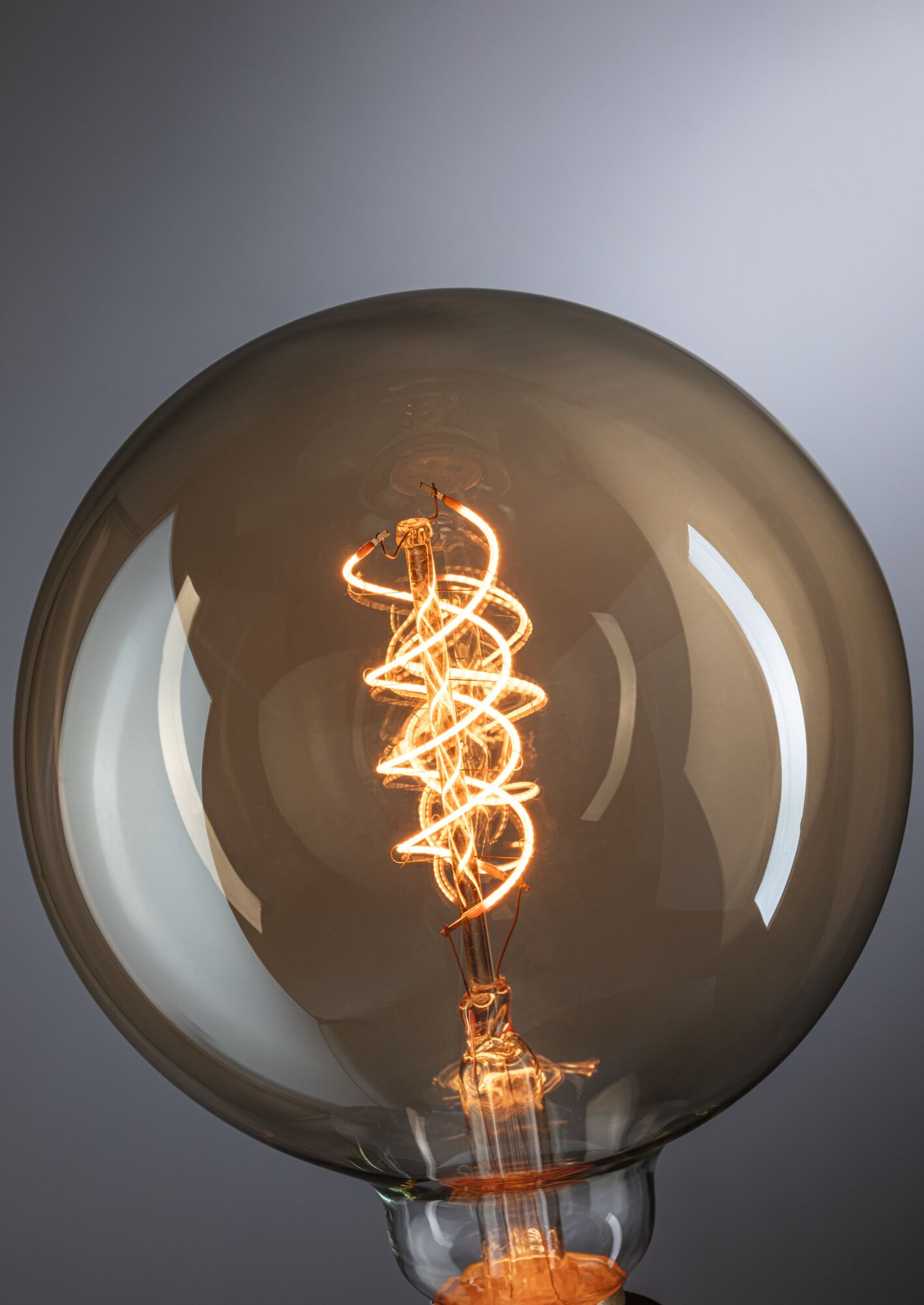 Nahaufnahme einer großen, runden, braunen Glühbirne mit einem glühenden, spiralförmigen Glühfaden.