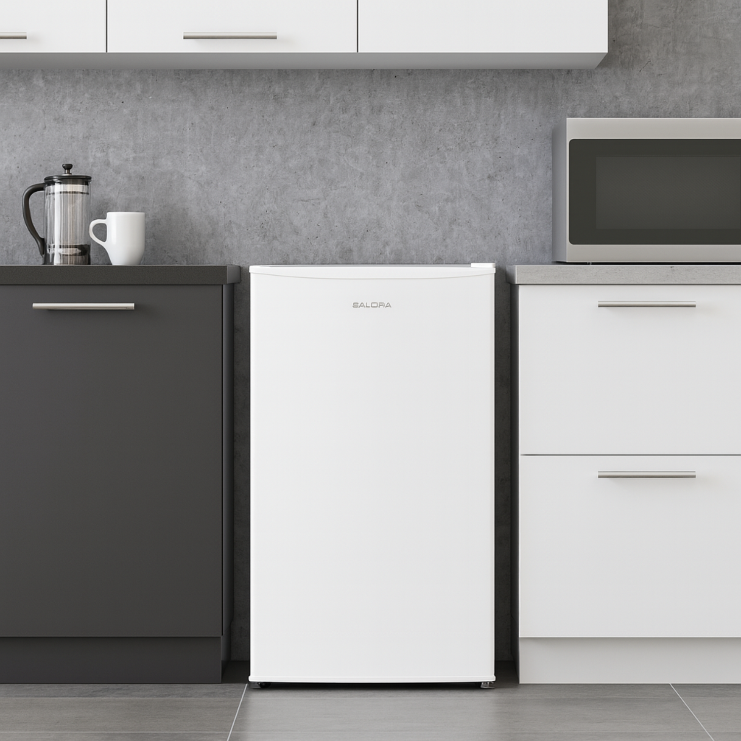 A white mini-fridge is between white and gray cabinets. A microwave and a coffee maker are on the countertops. A white mug is next to the coffee maker.